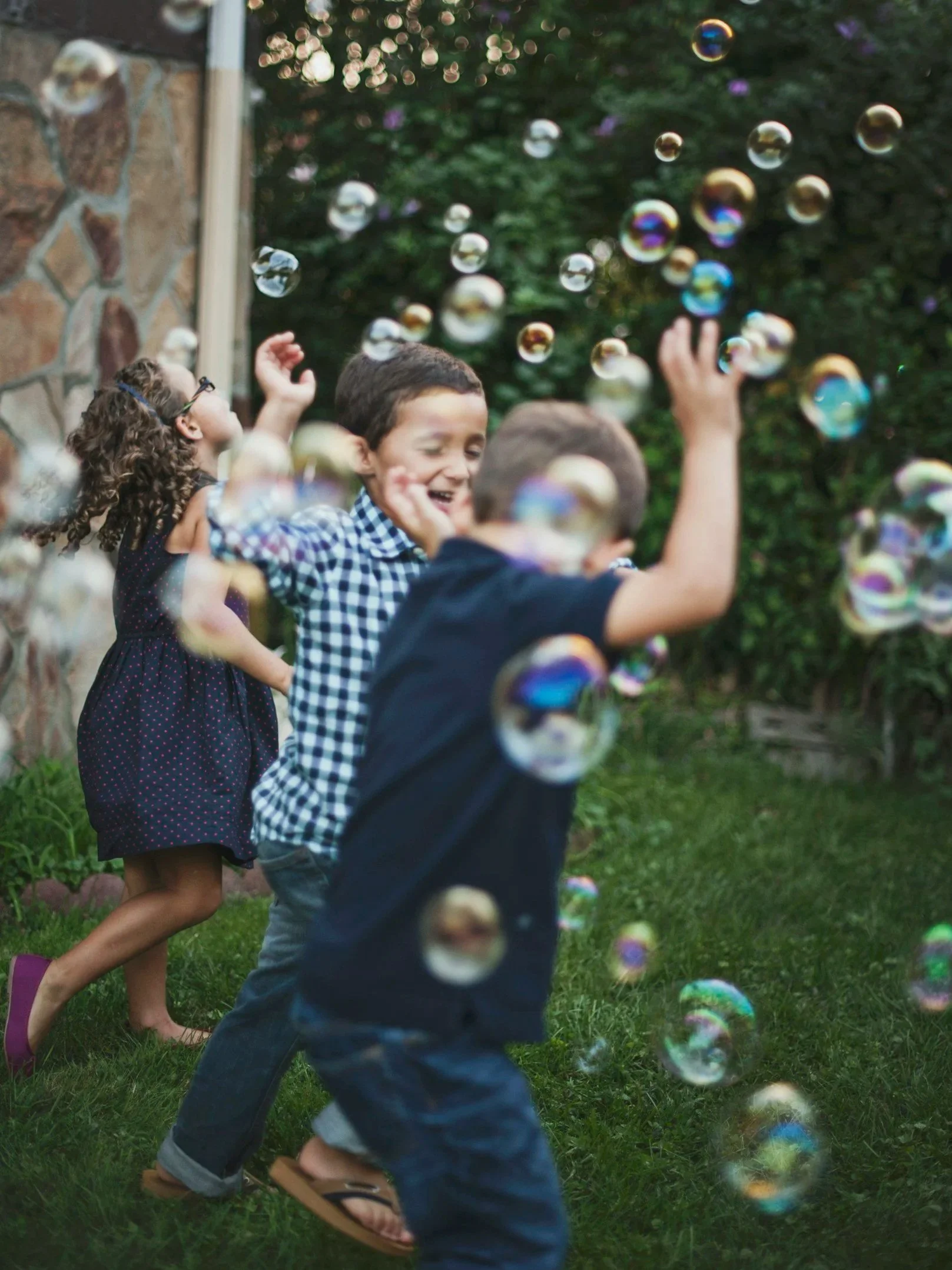 Kinder spielen im Garten mit Seifenblasen, lachen und haben Spaß.