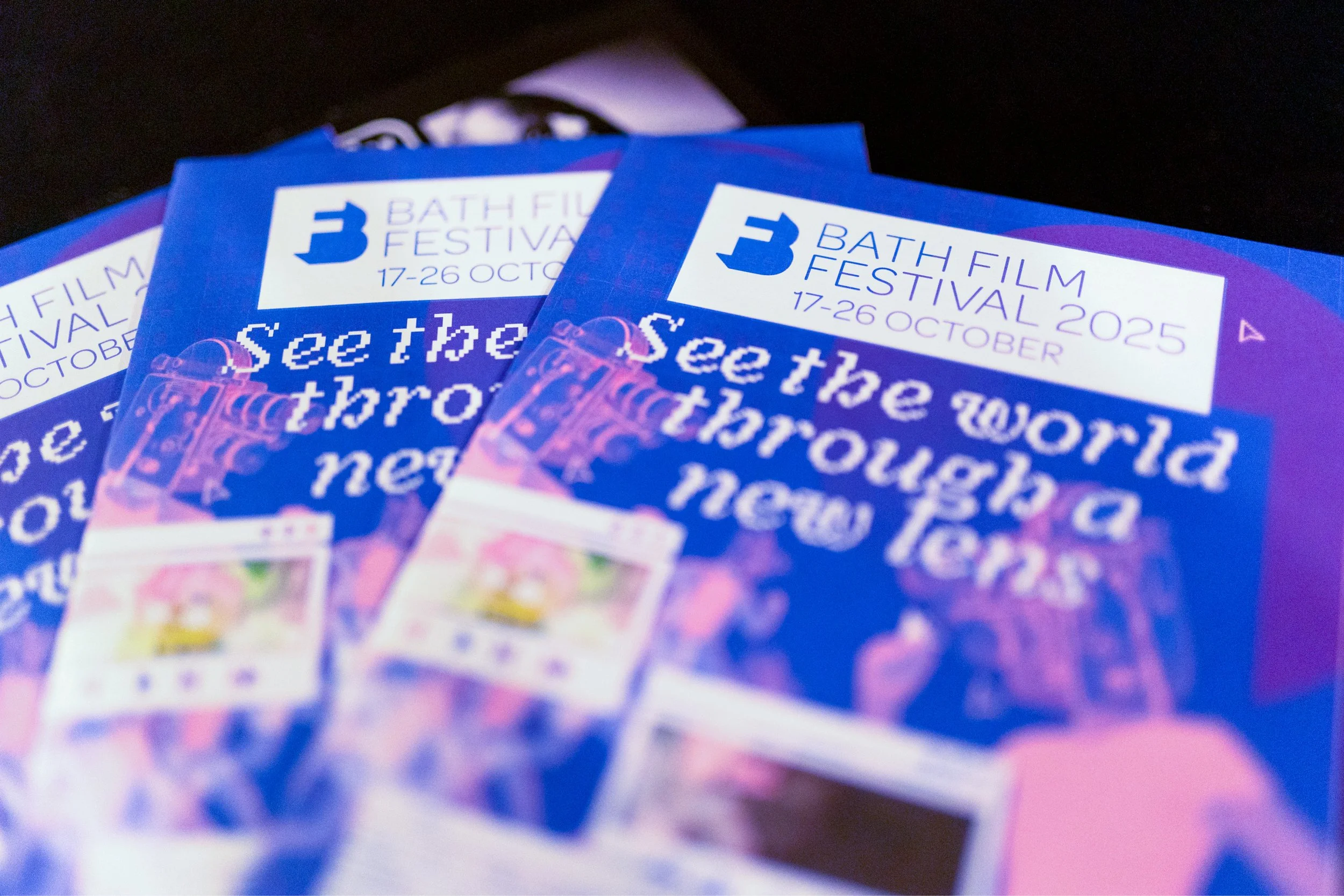 Bath Film Festival 2025 programmes with the line “See the world through a new lens” in retro pixel-style graphics.