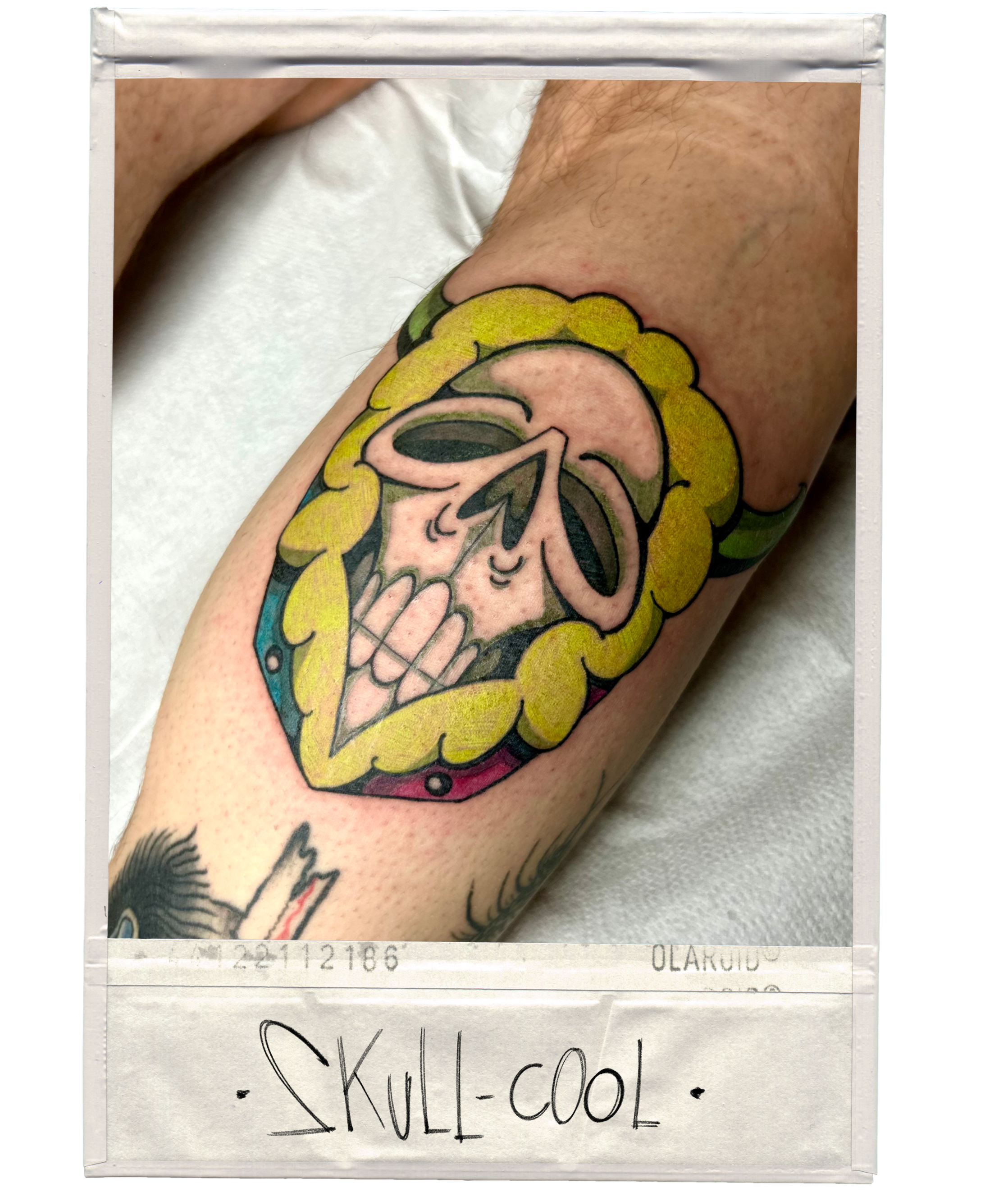 Tattoo of a cartoon skull with a yellow border and a gray shadow, located on a person's upper arm.