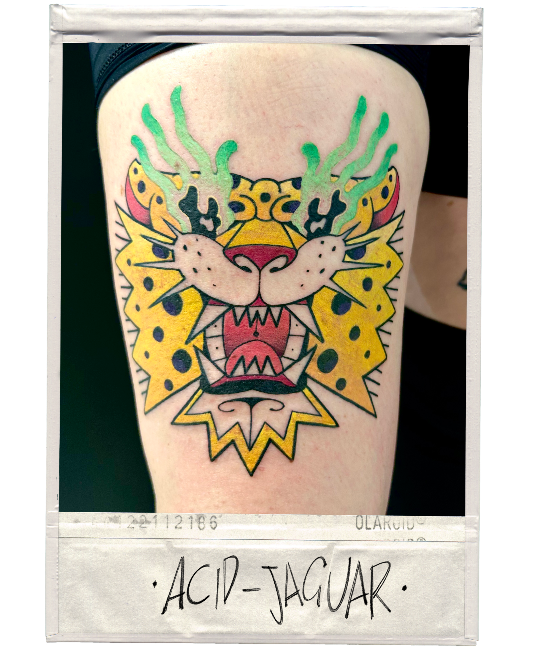 Tattoo of a colorful jaguar's face with green smoke-like details above the head, yellow spots on the cheeks, red tongue, and sharp teeth, labeled 'ACID-JAGUAR' at the bottom.