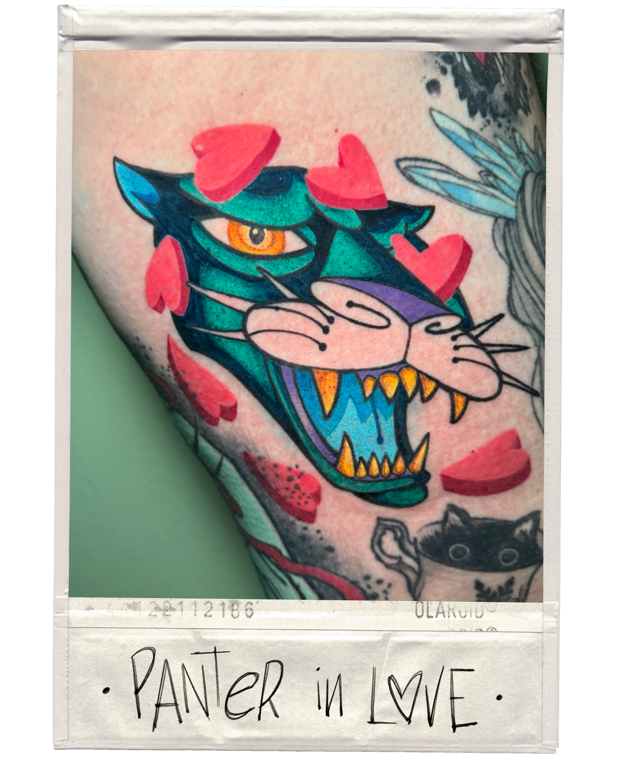 Tattoo of a colorful, stylized panther with an open mouth, sharp teeth, and orange eyes, surrounded by red heart-shaped confetti on the arm. Handwritten note below reads 'PANTER IN LOVE' with a heart symbol.