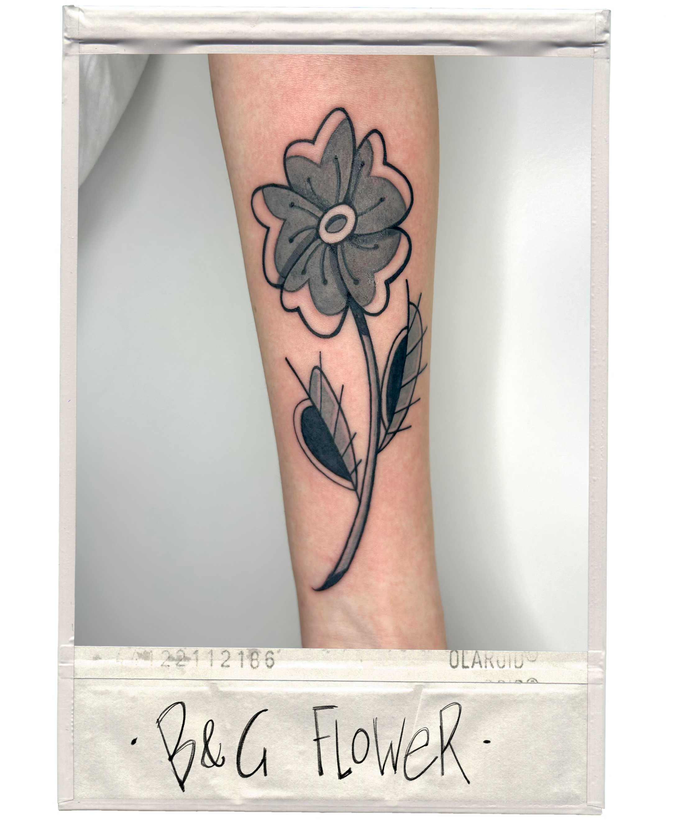 Tattoo of a large, stylized flower with leaves on a person's forearm.