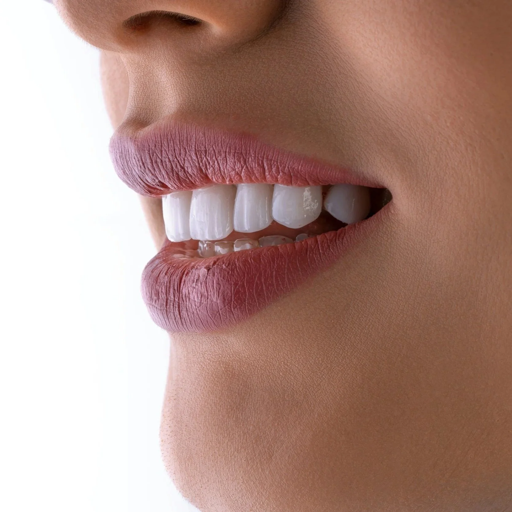 Primera plana de una boca con labios rosados y dientes blancos, sonriendo ligeramente.
