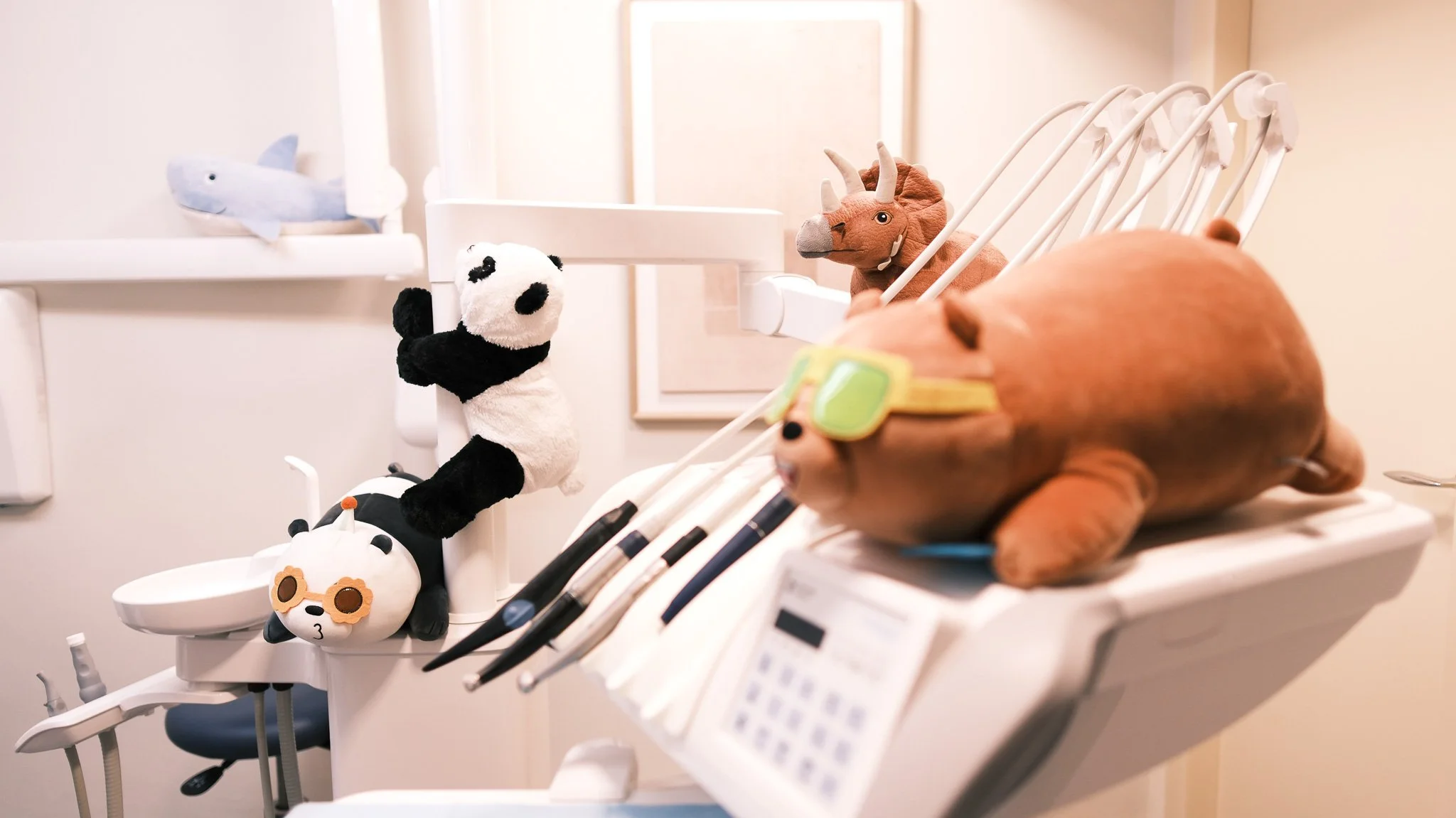 Sala de tratamiento dental decorada con peluches de animales, incluyendo un panda, una ballena, un rinoceronte y un atún