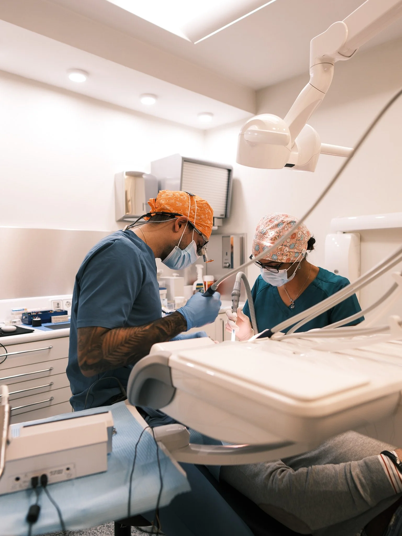 Dos dentistas trabajando en un procedimiento dental con equipo médico en una clínica dental moderna.