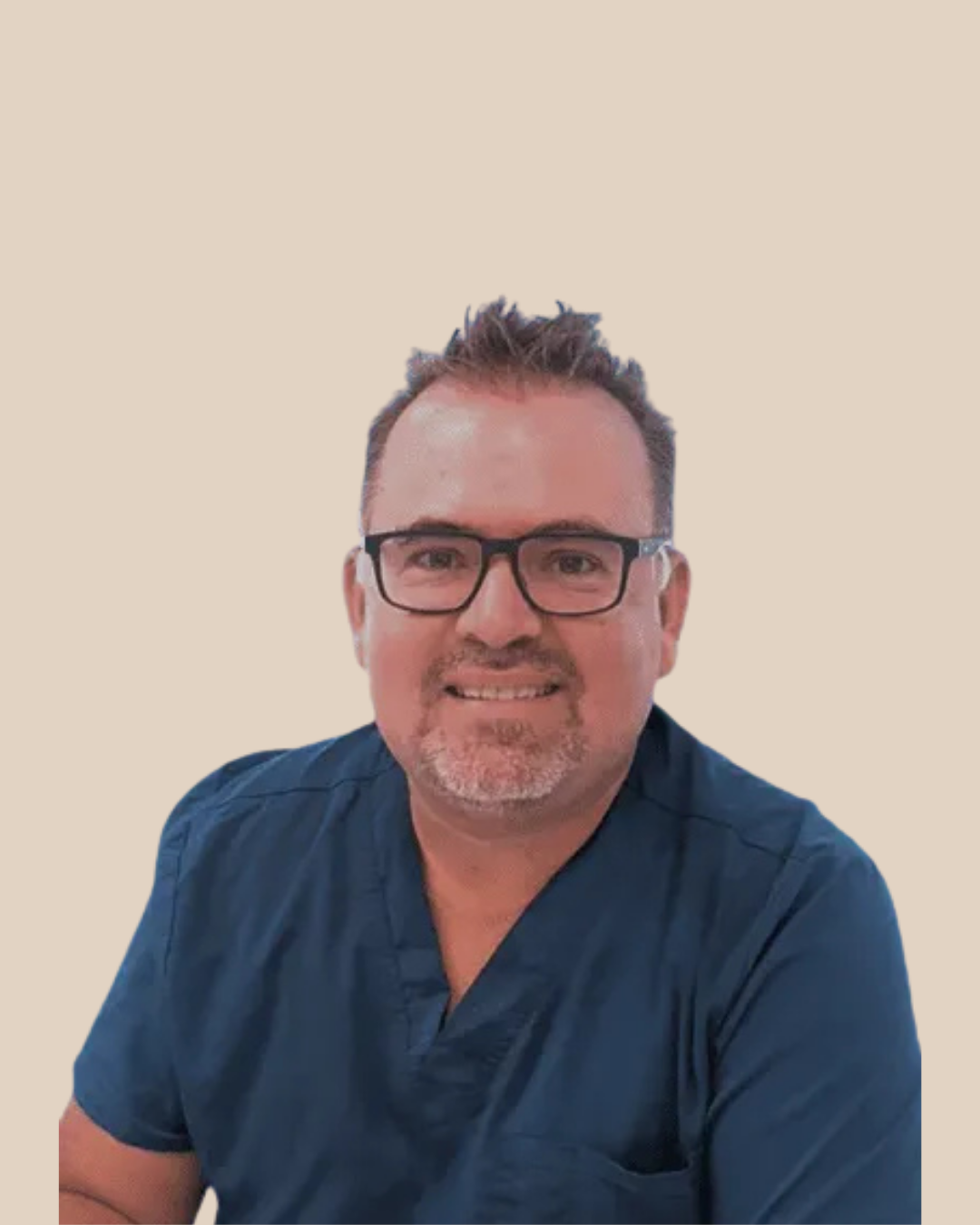 Retrato de un hombre con gafas, barba y peinado corto, vistiendo una camiseta azul, sonriendo, fondo beige.