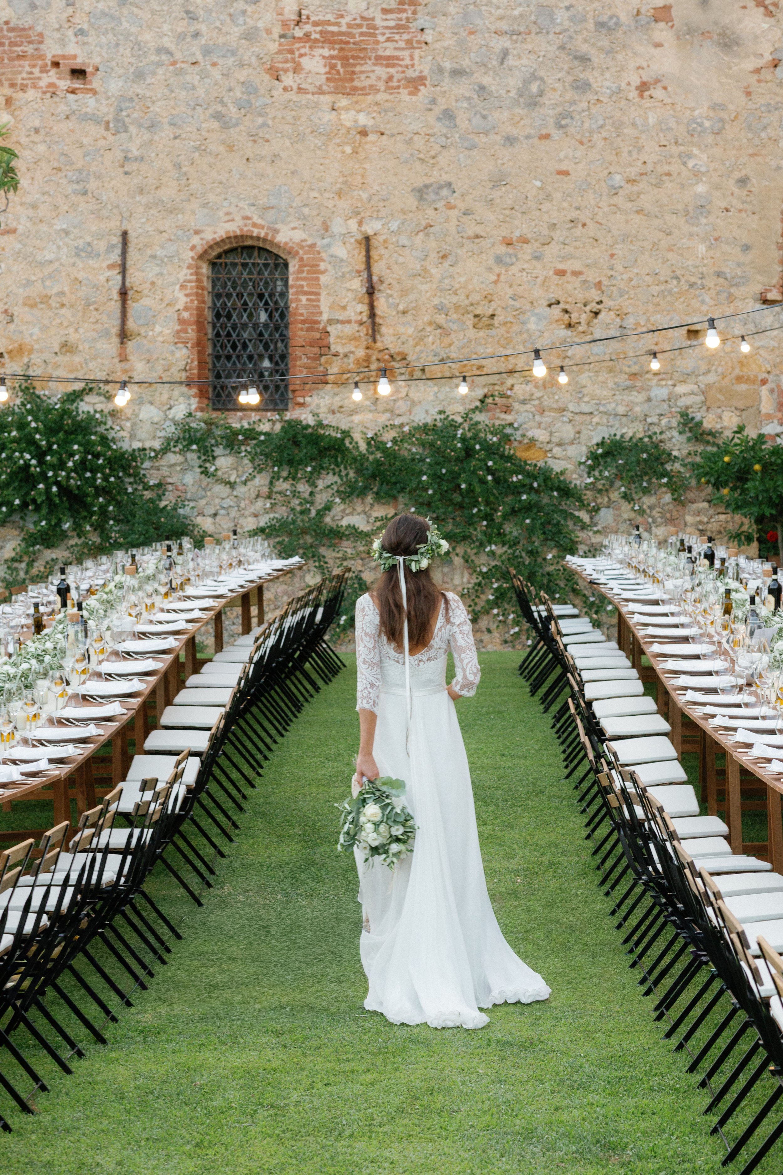 Bride walking through outdoor table setting for a destination wedding in Tuscany, Italy.