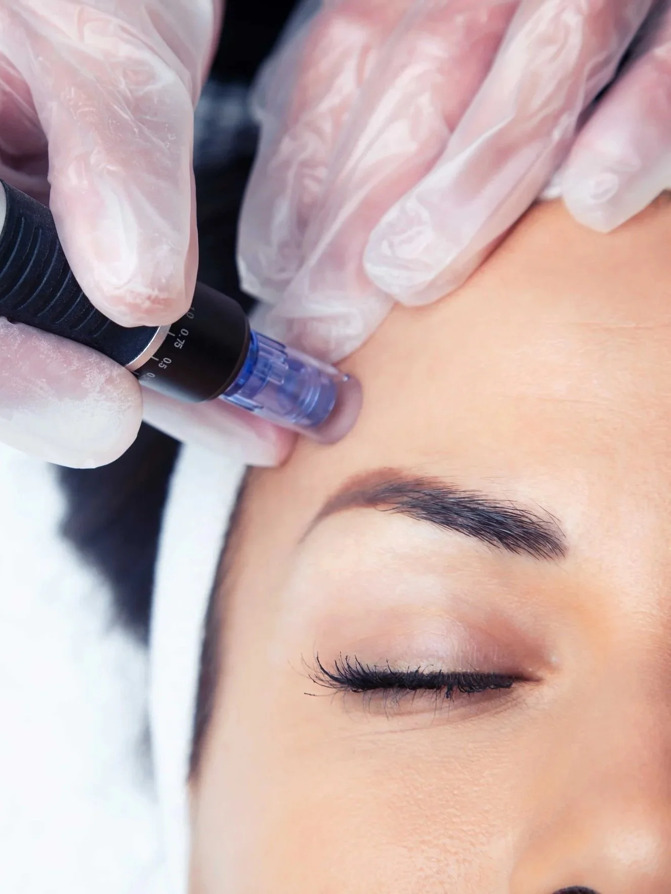 En person får permanent makeup på øyenbrynene av en estetiker iført plasthansker.