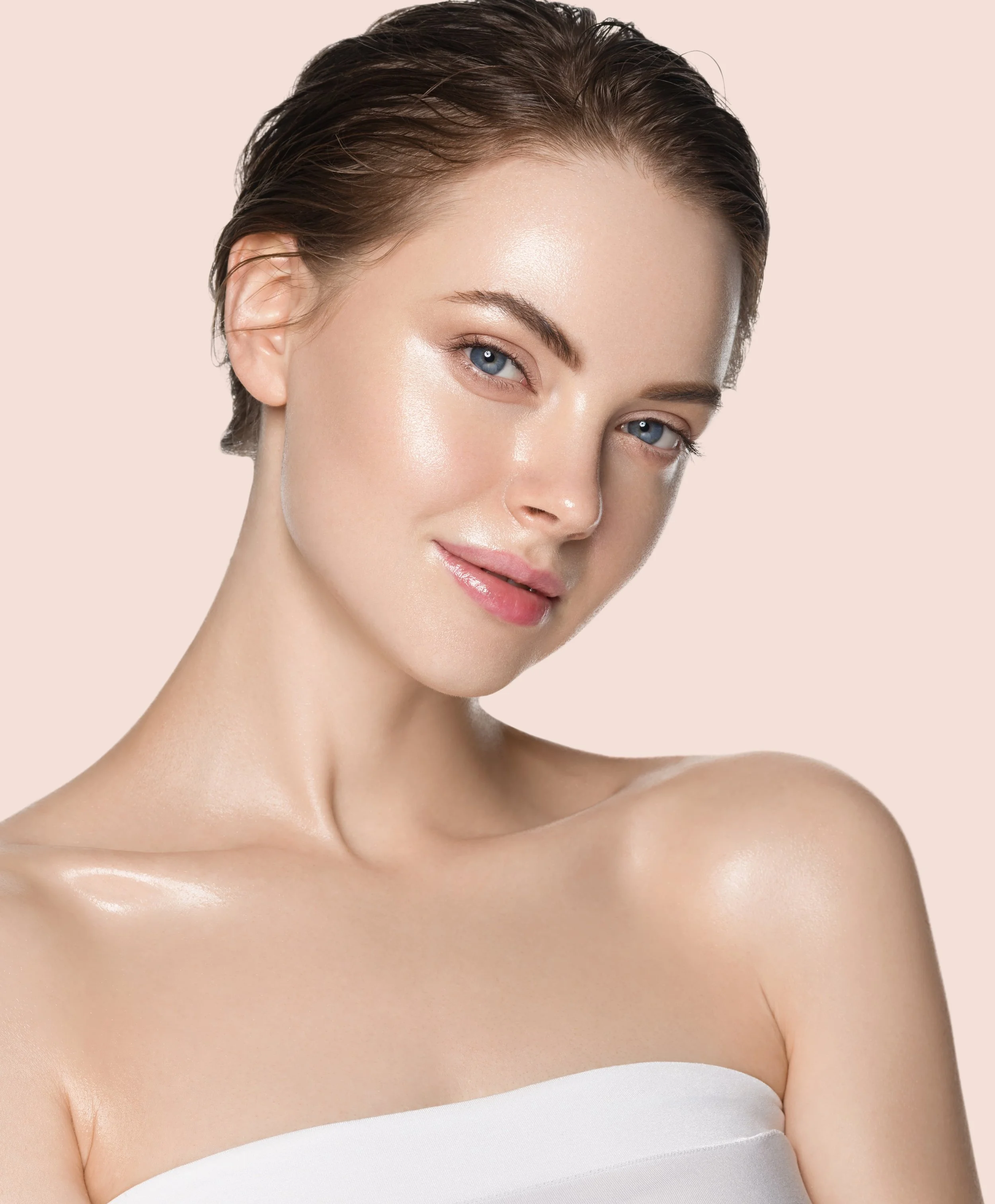 Portrett av en ung kvinne med blank hud, lette øyne og kort, vått hår, mot en lys rosa bakgrunn.