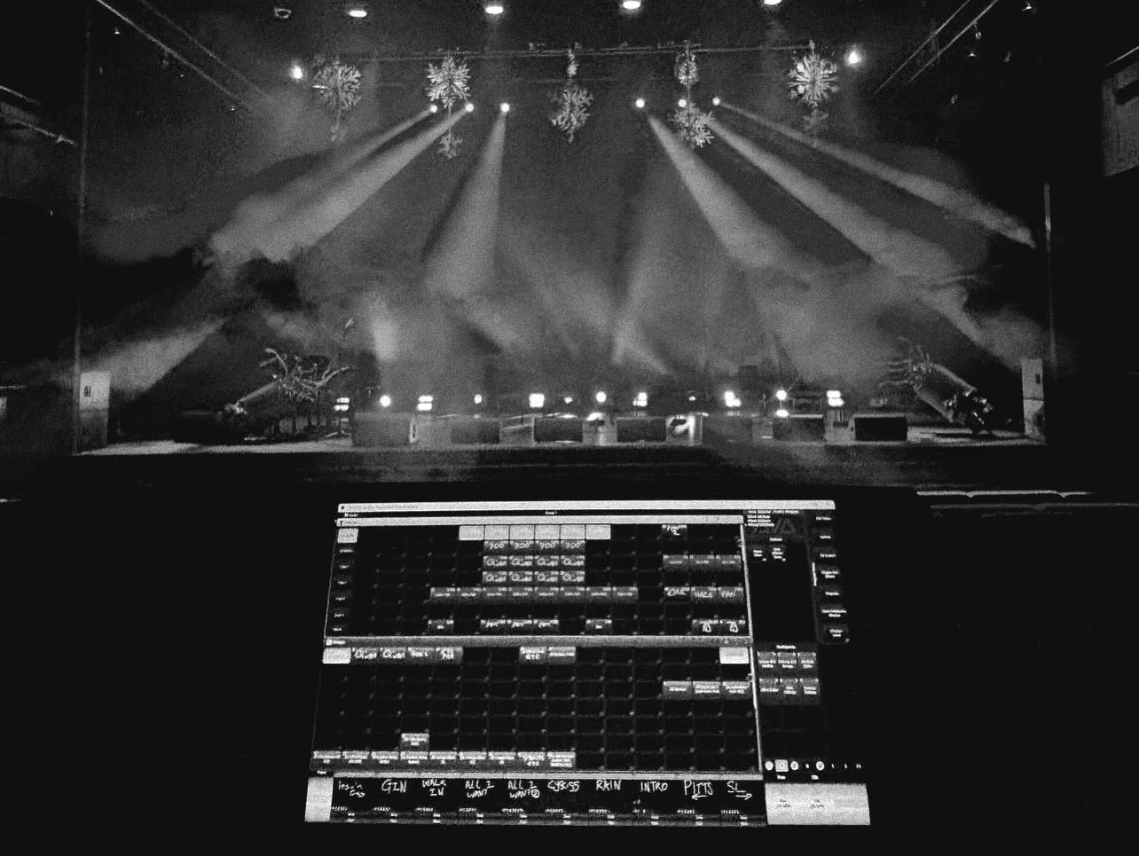A DJ controller or mixing console is in foreground, with a stage in the background illuminated by spotlights and decorated with hanging snowflakes, suggesting a winter or holiday event.