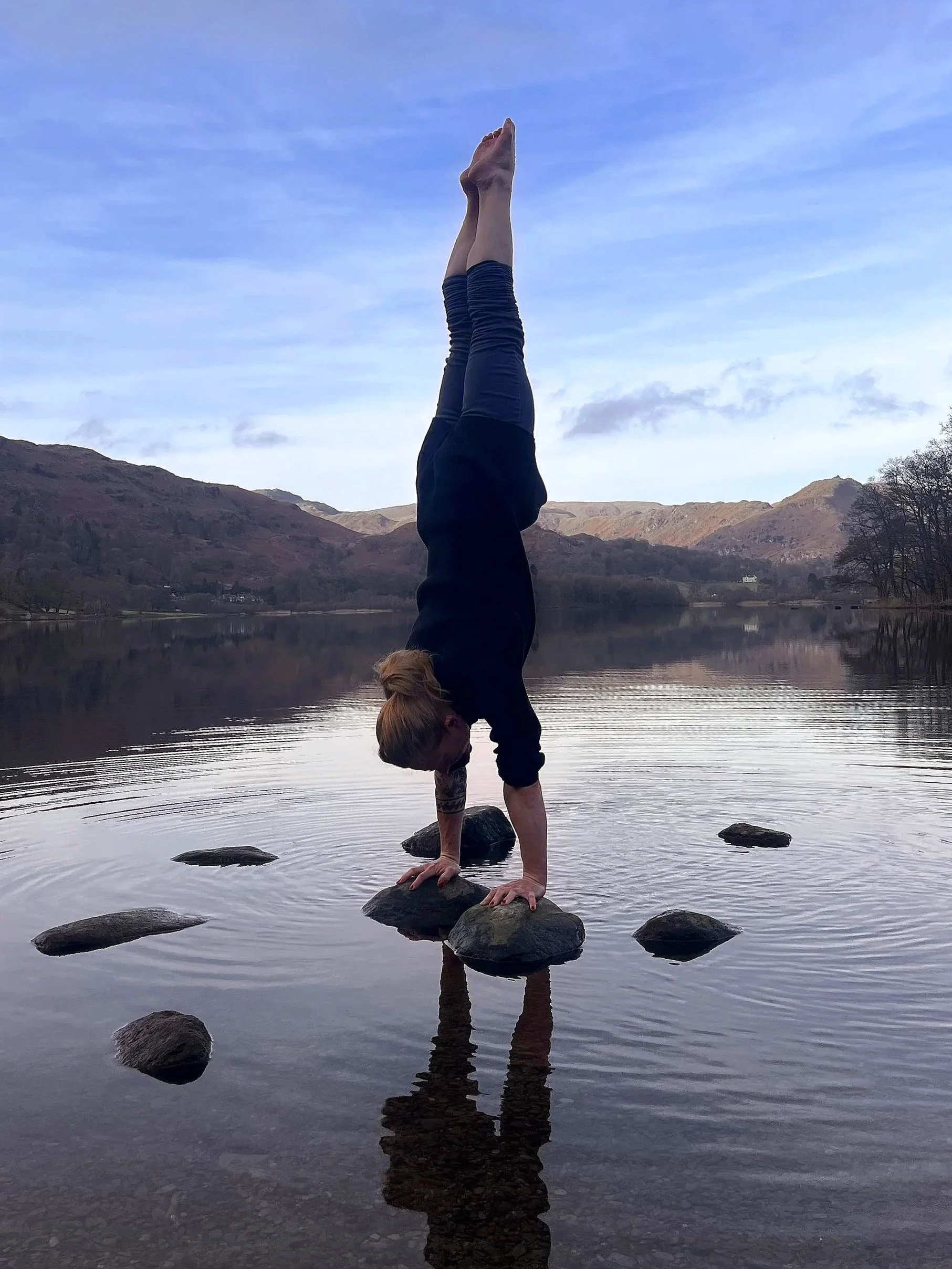 joey doing a handstand on two hand-sized rocks sticking out of the surface of a lake