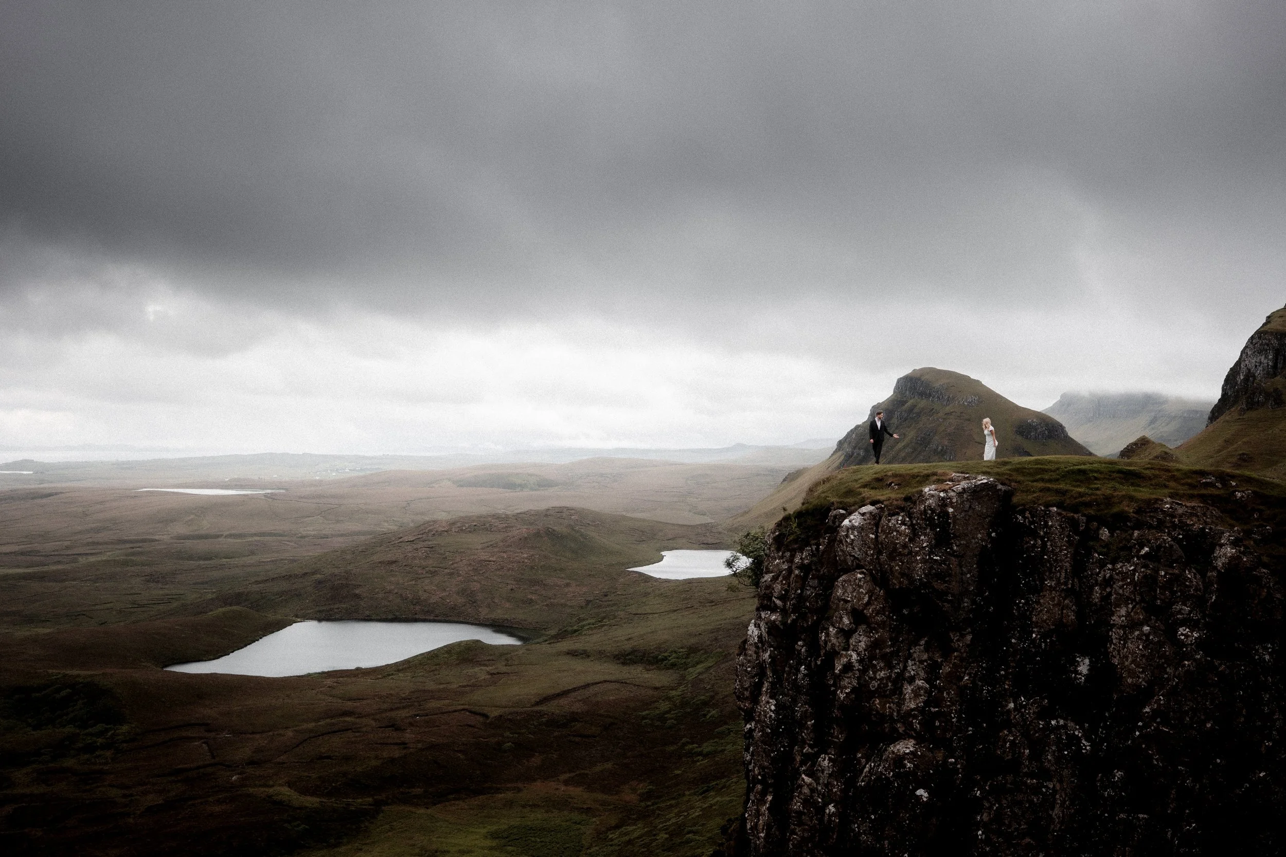 Couple standing on cliff edge overlooking dramatic Isle of Skye landscape during elopement