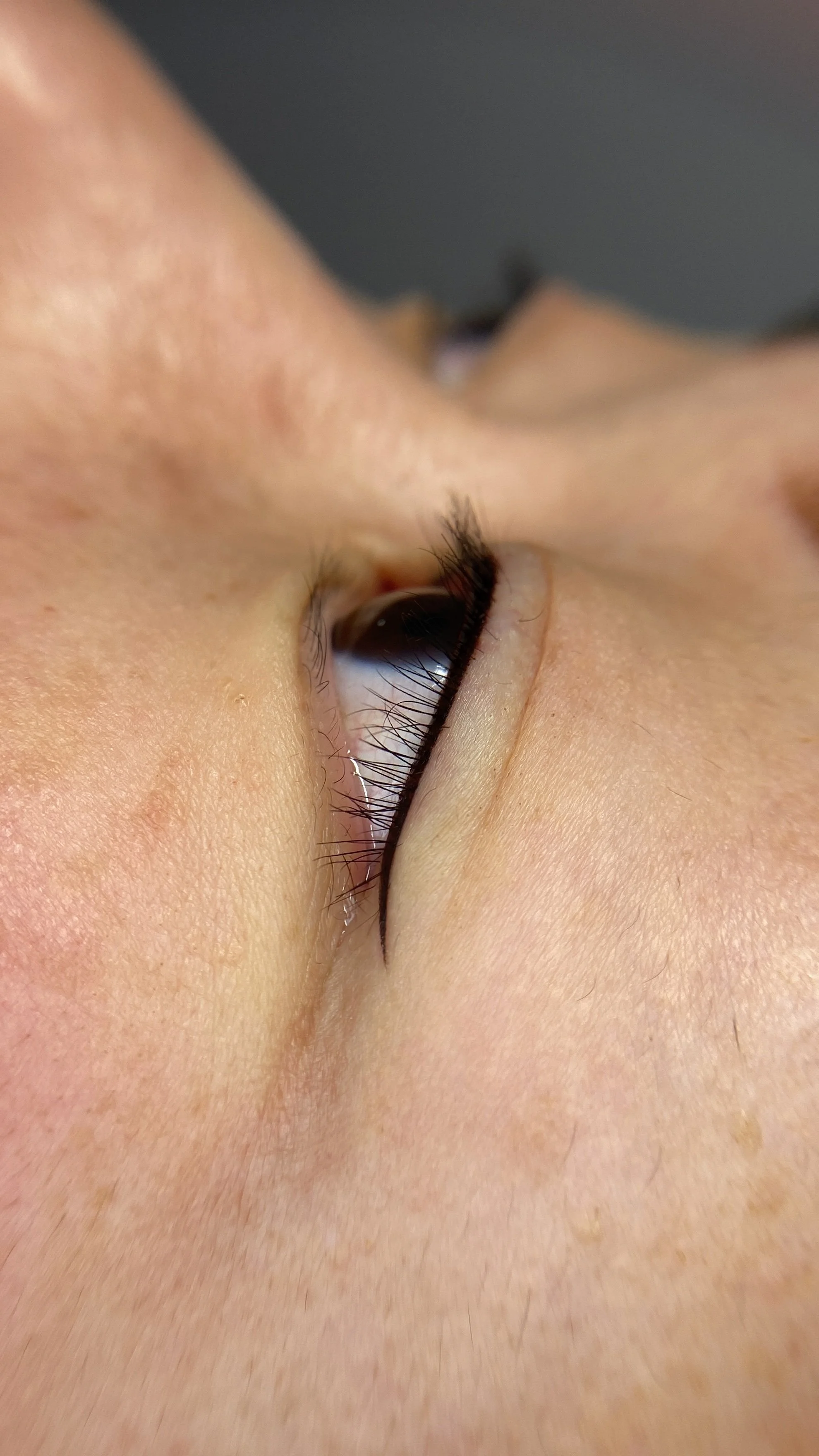 Close-up of a person's face, focusing on the eye with makeup and long eyelashes.