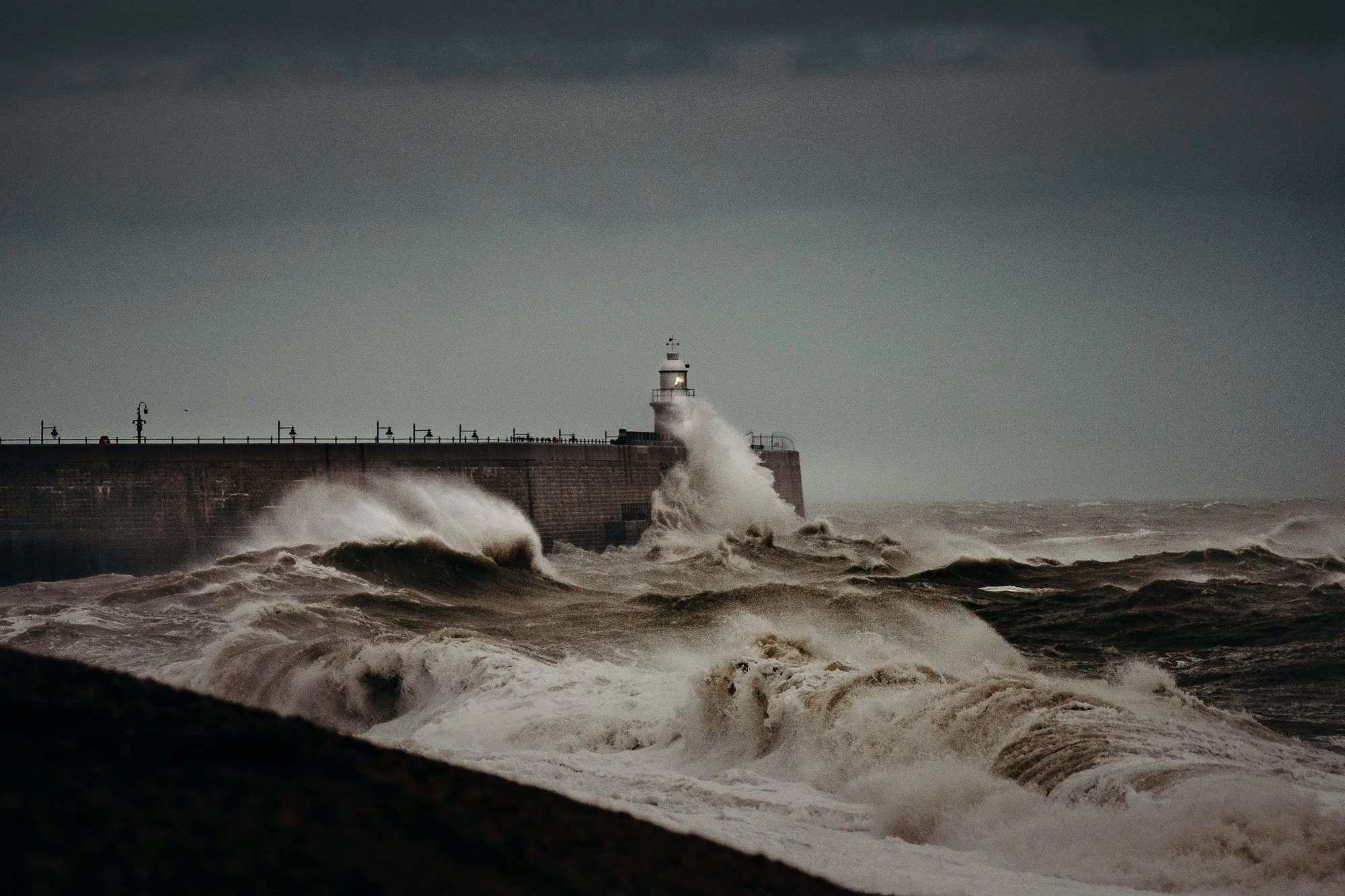 A stormy scene with waves crashing against a pier