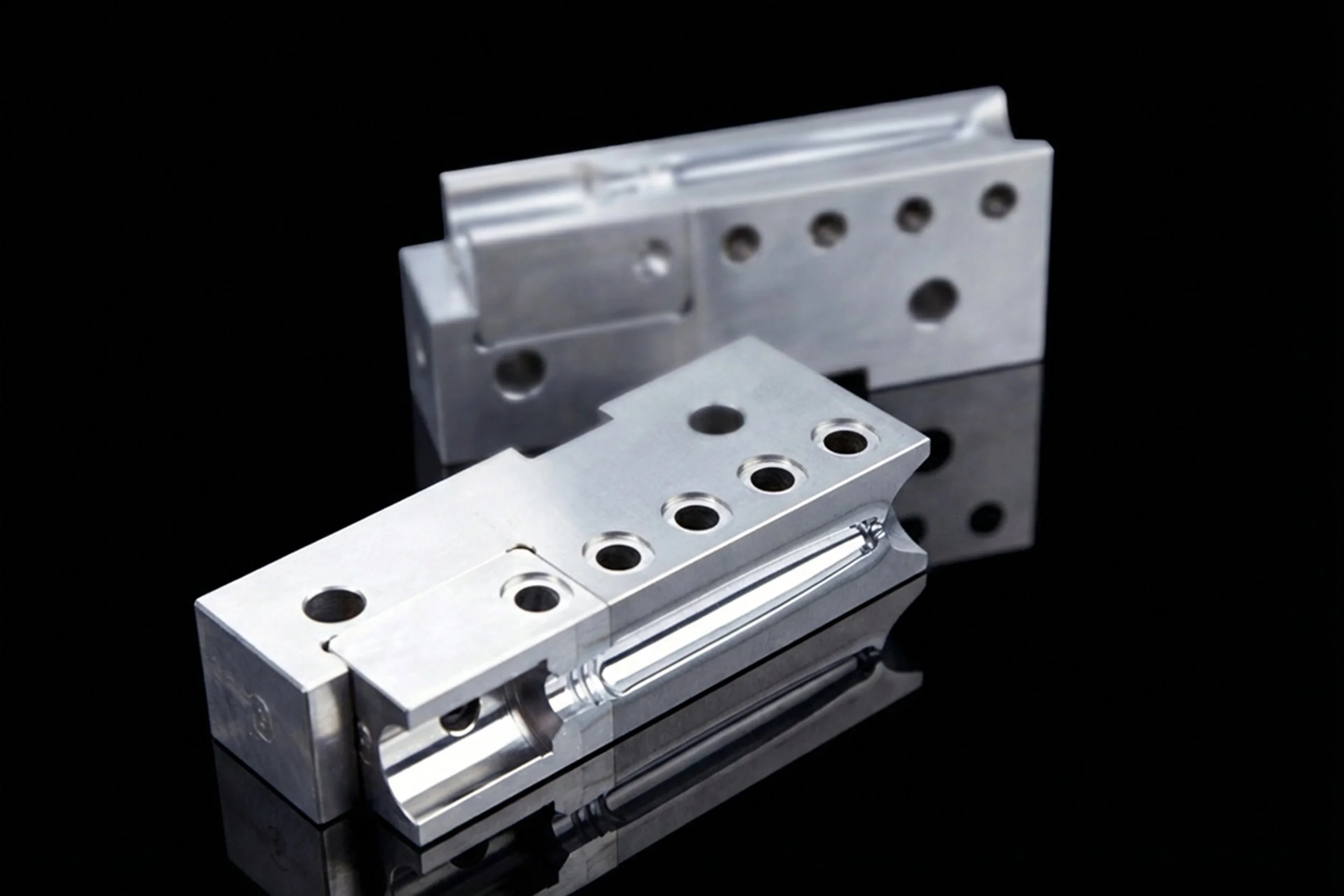 Zwei präzise metallische Maschinenteile auf einem schwarzen Hintergrund.