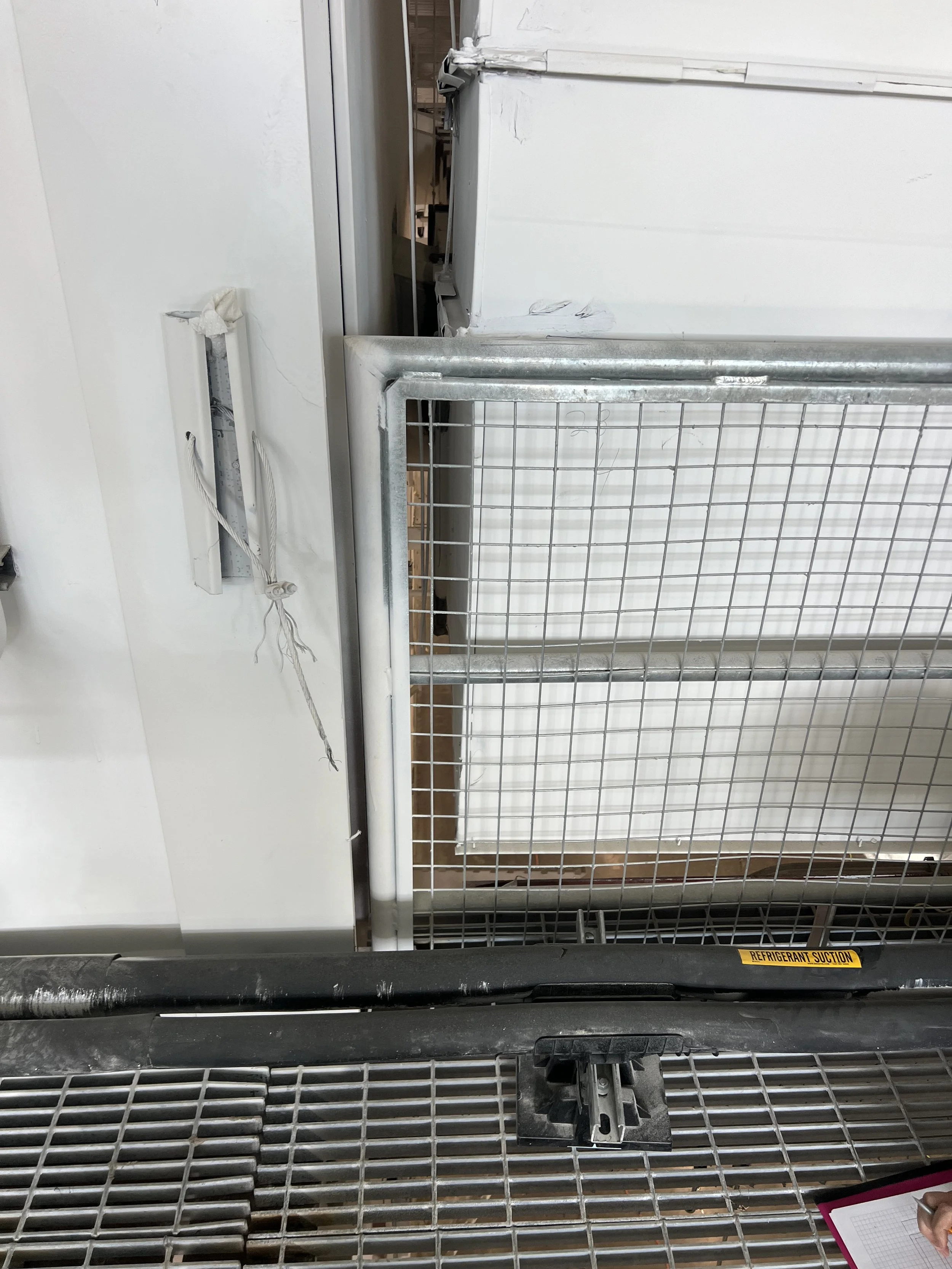 Industrial refrigeration refrigeration system with pipes and metal grid, with a label indicating refrigerant suction.