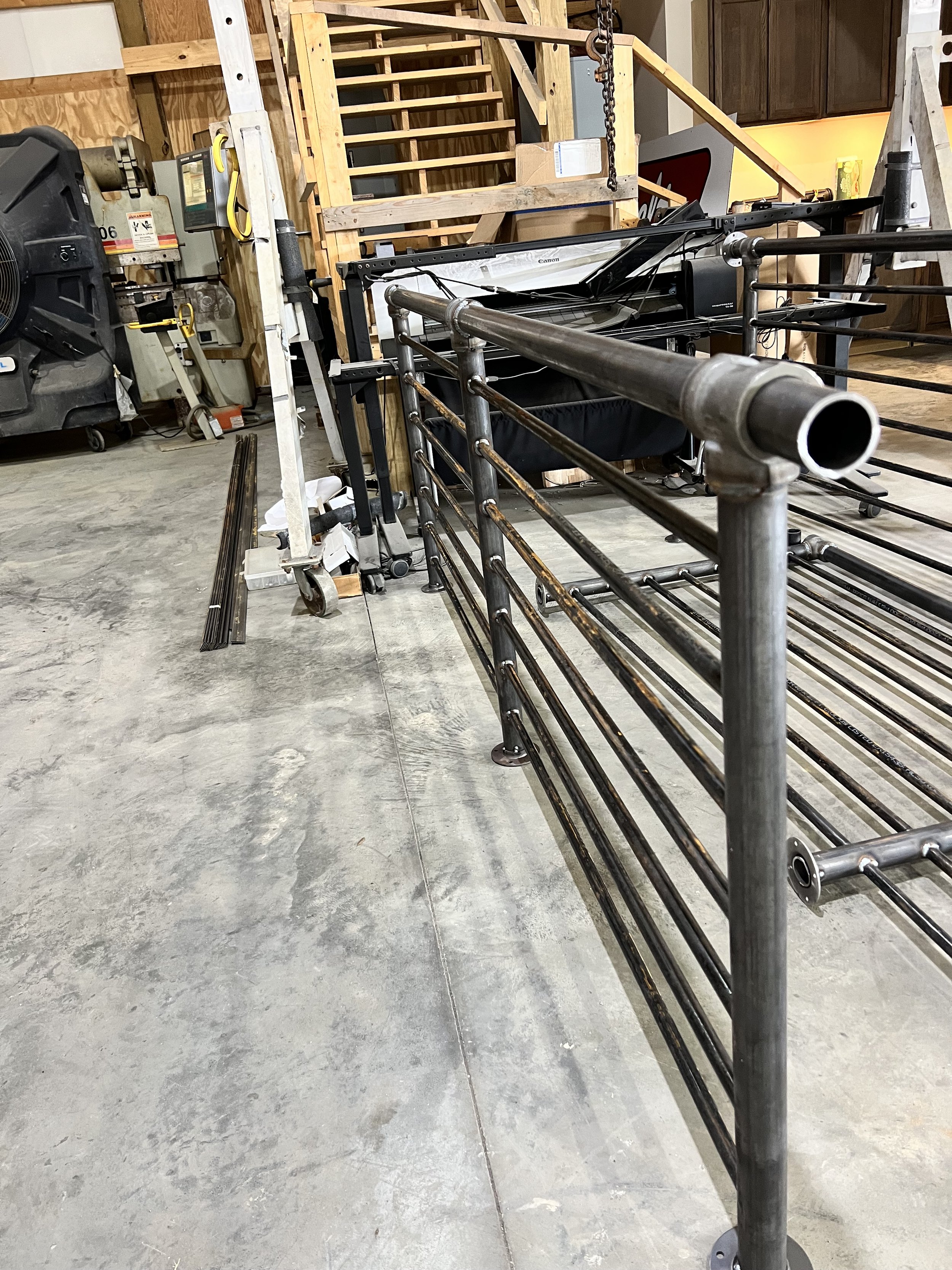 A metal railing with horizontal bars in the foreground of a workshop or garage.