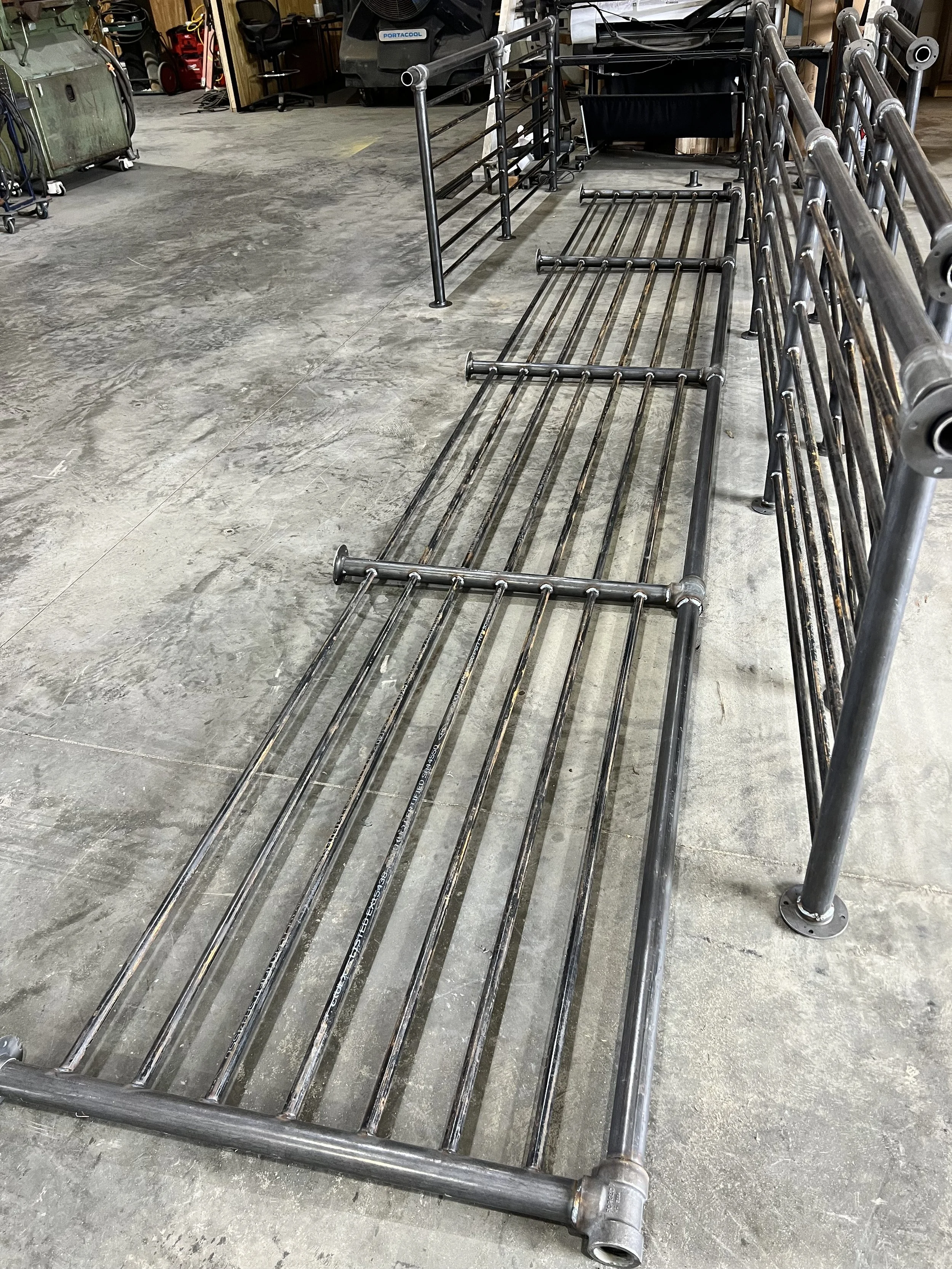 Metal retail display racks lying on the concrete floor in what appears to be a warehouse or workshop.