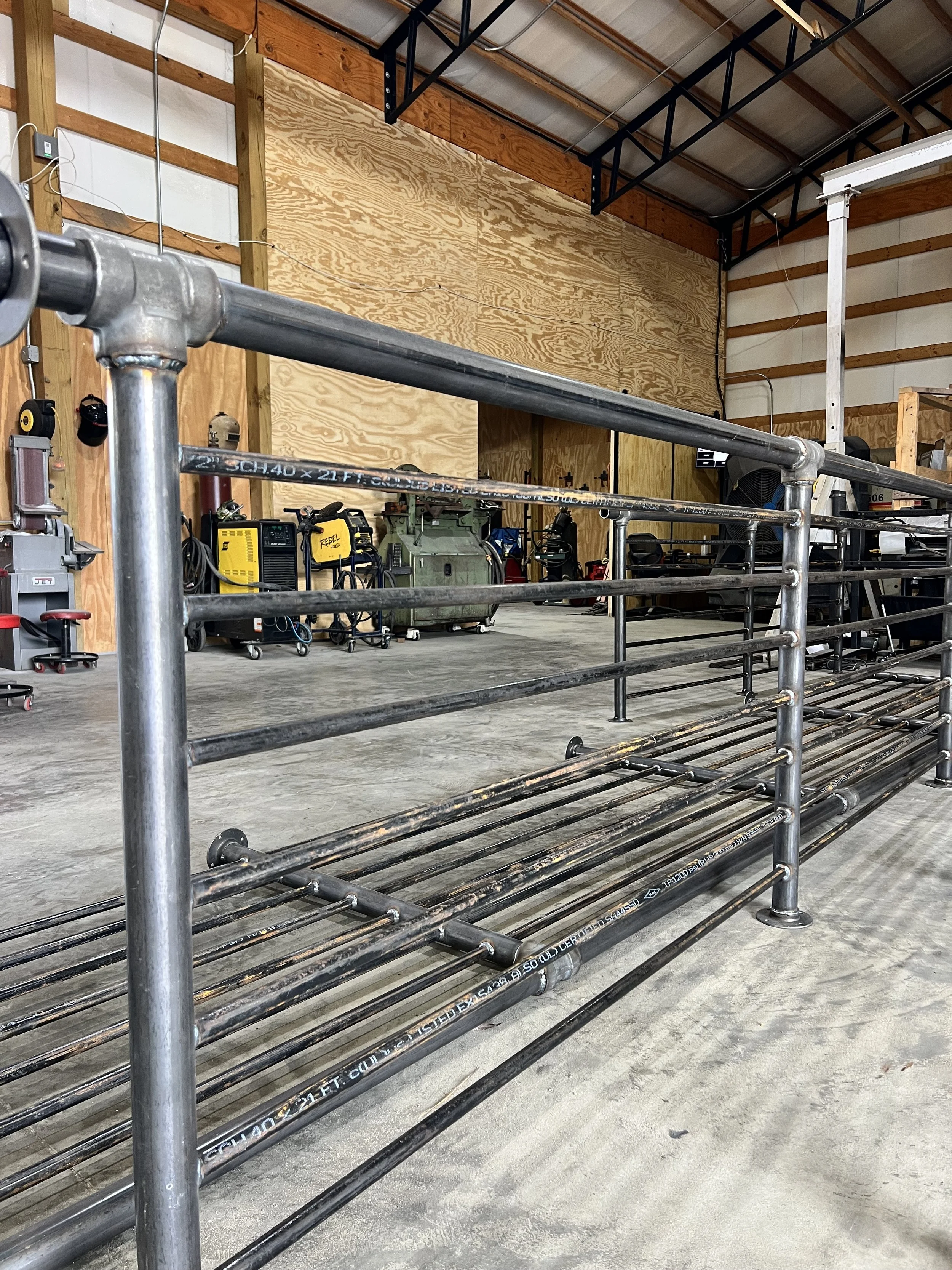 Empty metal pipe rack in a workshop with tools and equipment in the background.