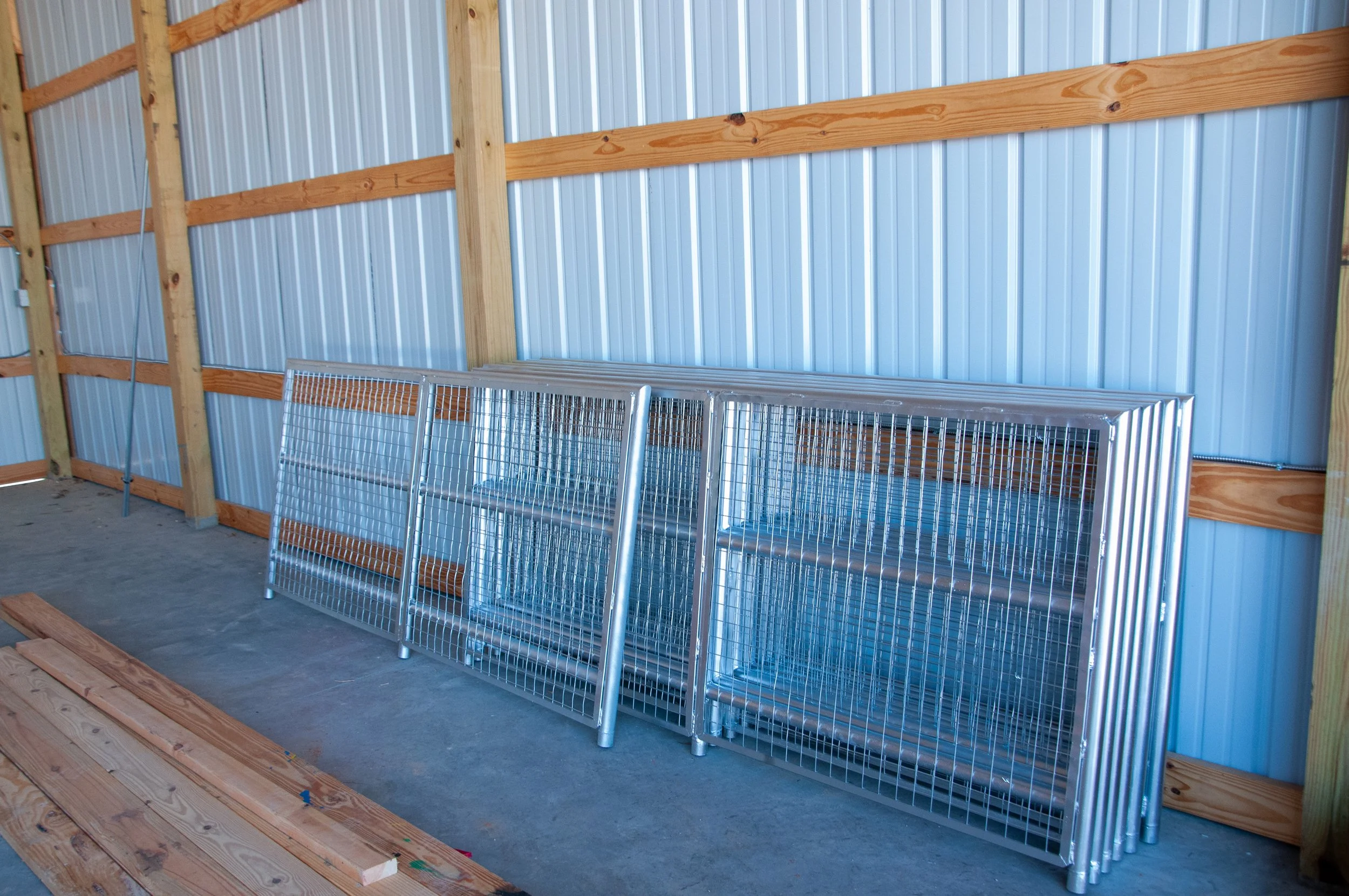 Metal wire storage racks leaning against a blue metal wall inside a wooden-framed shed.