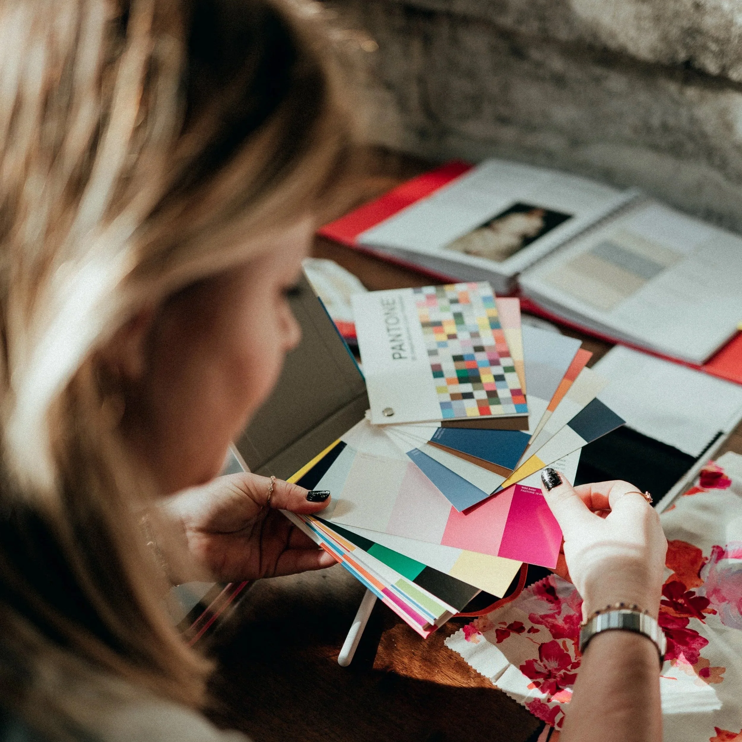 Une femme regarde des échantillons de couleurs et de textures pour le design de sa collection de prêt-à-porter.
