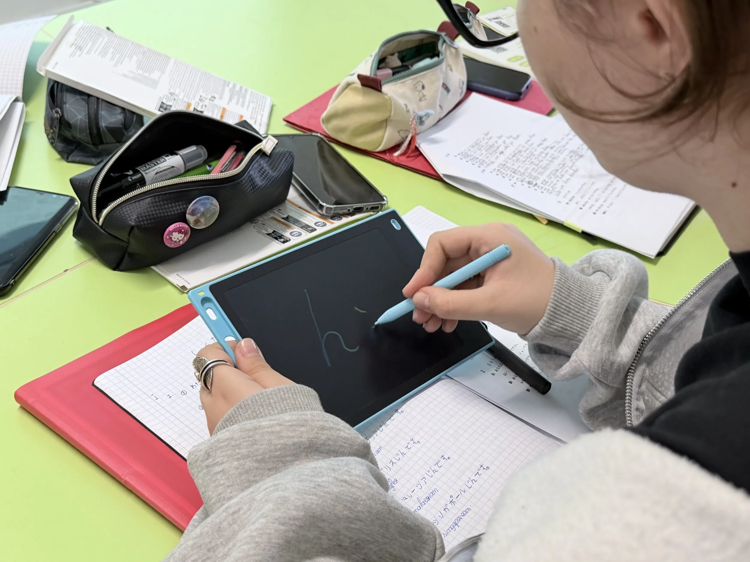 Cadru de aproape cu o elevă care exersează scrierea caracterelor japoneze pe o tabletă digitală cu stilou, în timpul orelor de curs York Rose Constanta
