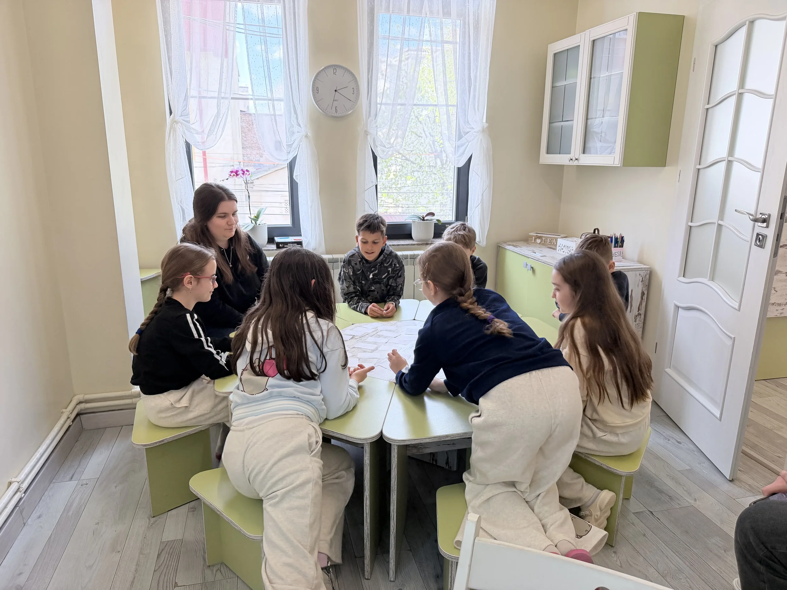 Grup de copii așezați la o masă modulară verde, lucrând împreună în timpul orelor de engleză la York Rose Constanța