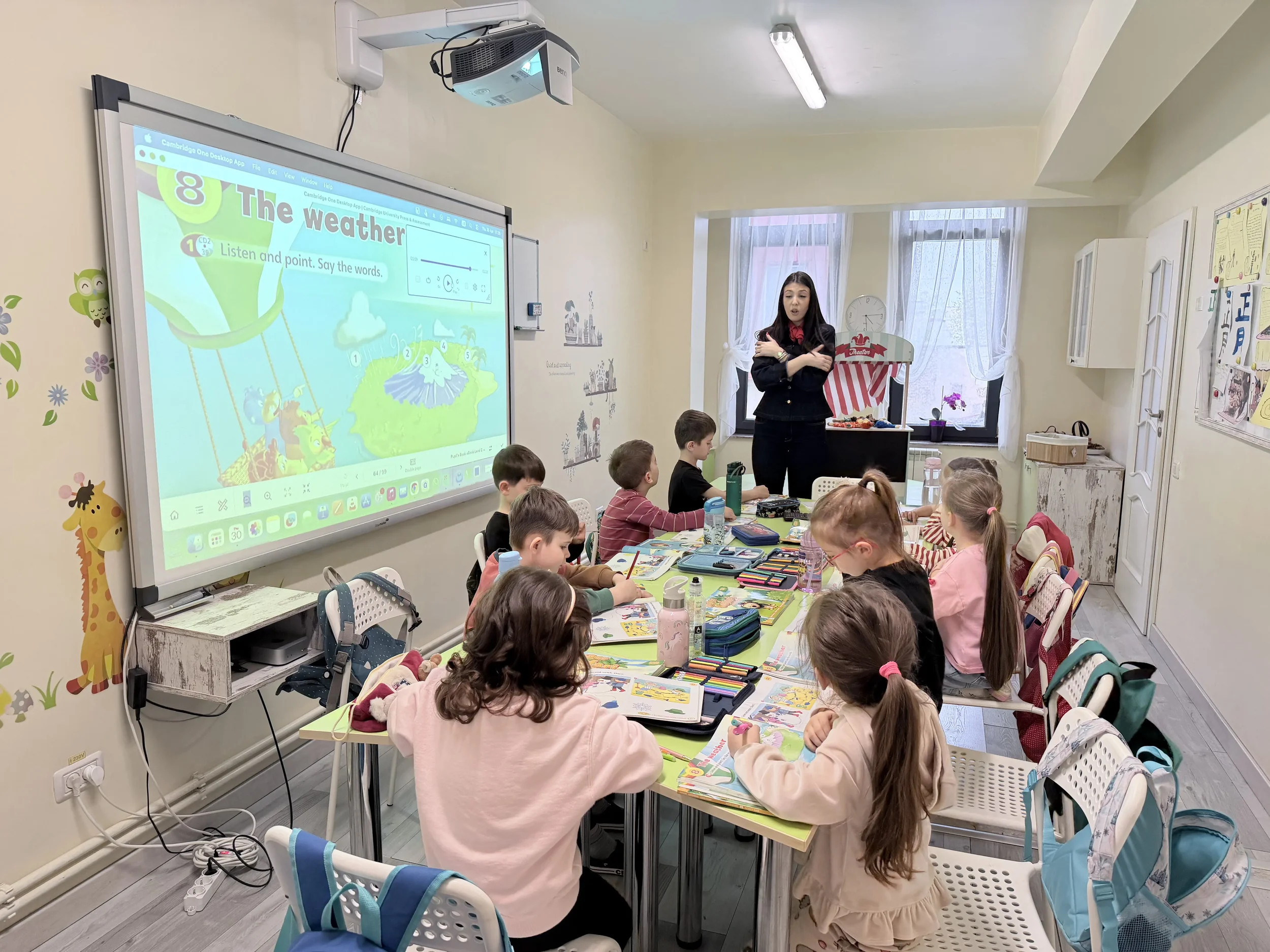 Teacher Alexandra susținând o lecție interactivă despre vreme cu o grupă de copii la școala de limbi străine York Rose din Constanța, utilizând manuale digitale Cambridge și o tablă inteligentă smart.