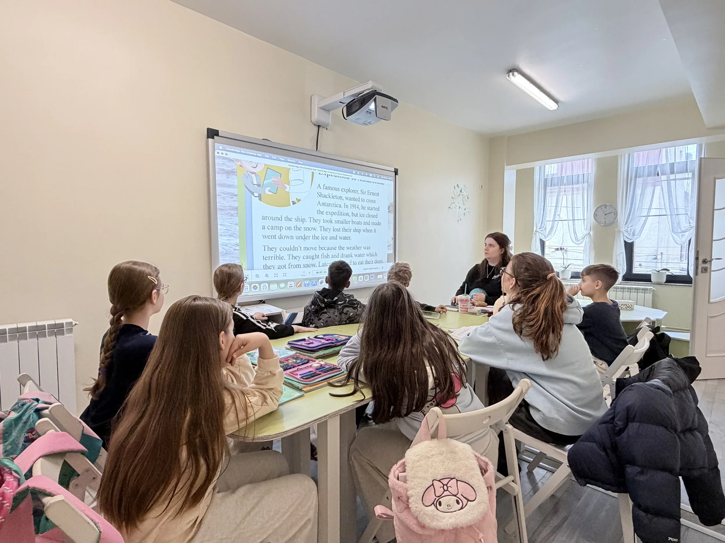 Un grup de copii preșcolari citesc concentrați din manualele lor în timpul unei activități interactive de grup axate pe dezvoltarea vocabularului.