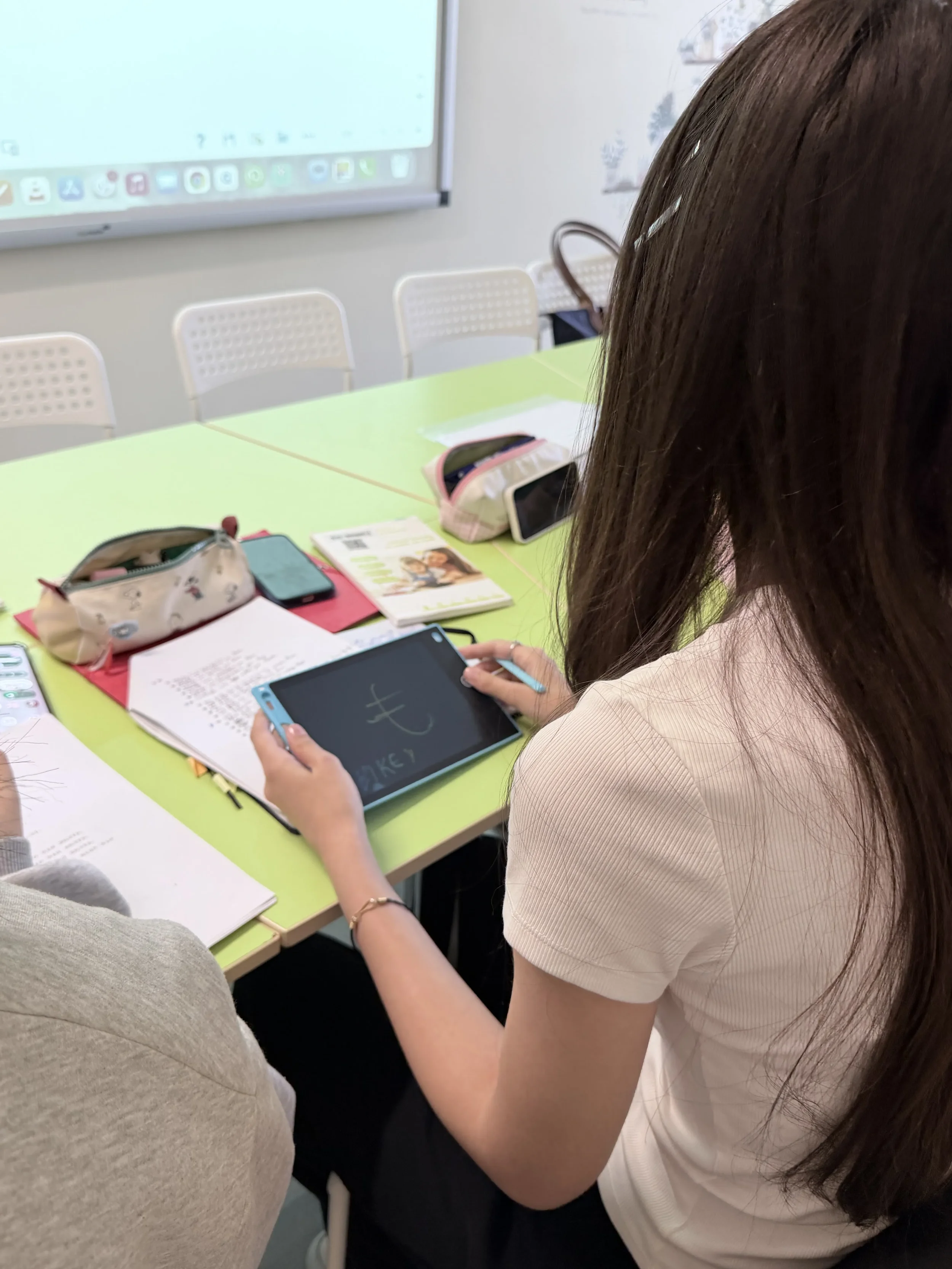 O cursantă cu părul lung exersează scrierea caracterelor japoneze pe o tabletă digitală cu stilou electronic, în timpul unui modul de limba japoneză la York Rose.