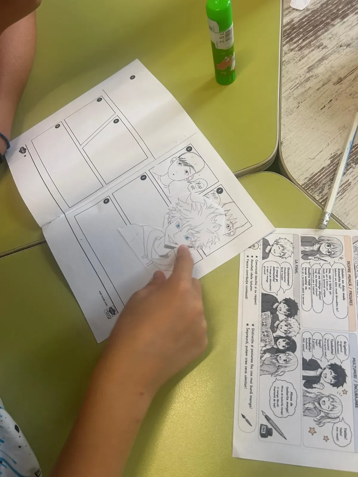 Cadru de aproape cu un elev lipind personaje manga în caietul de exerciții de limba japoneză