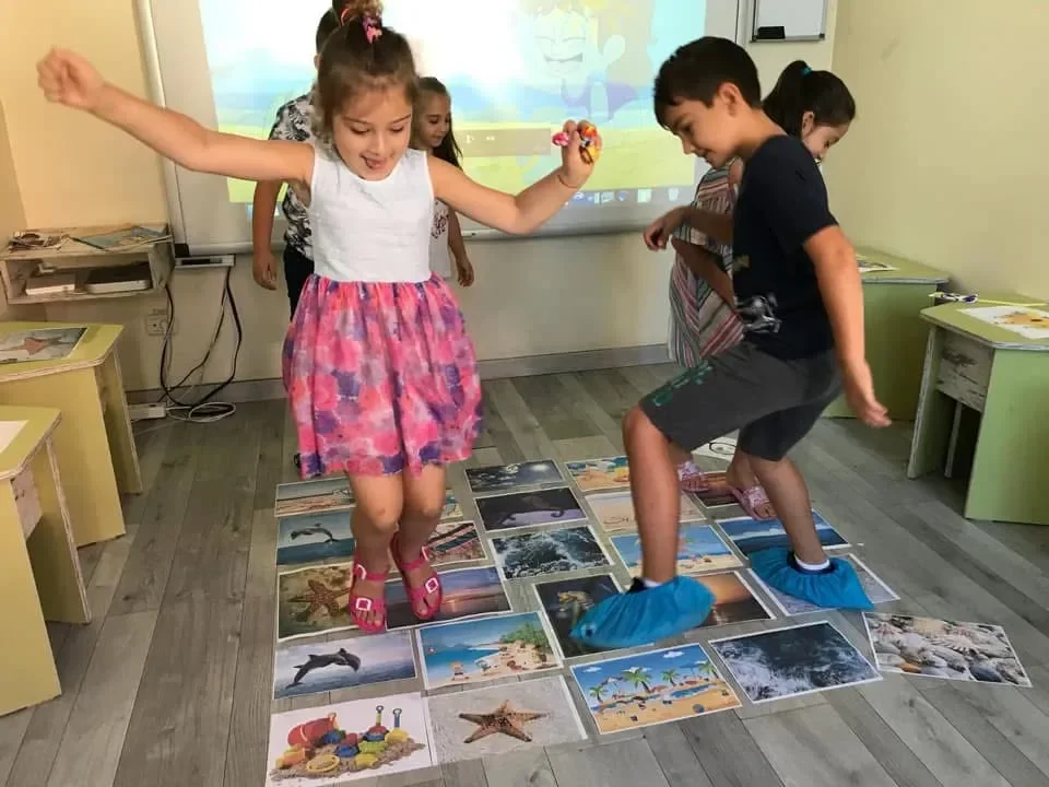 Copii la York Rose învățând vocabular prin joc interactiv cu imagini pe podea.