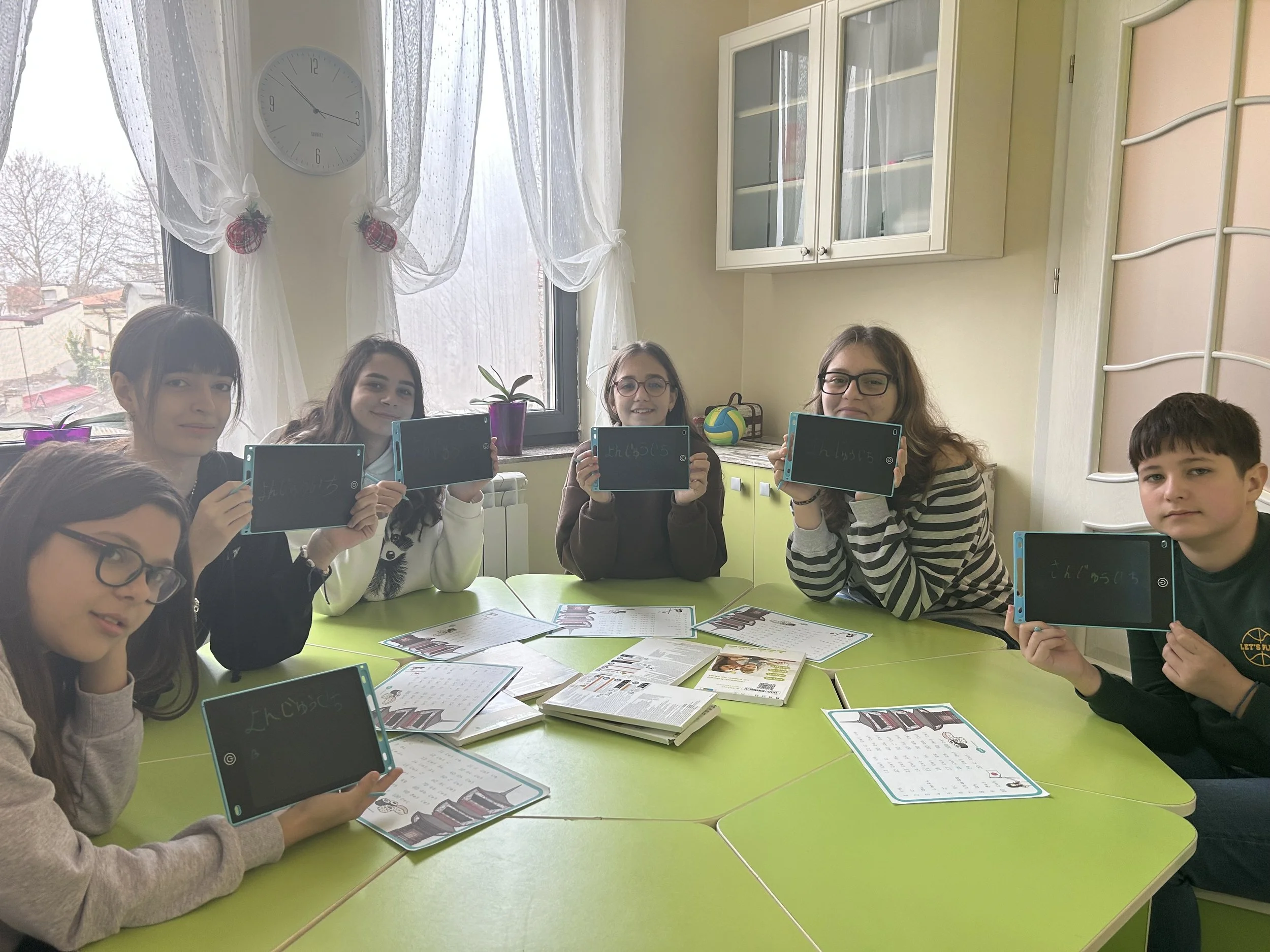 Elevi la York Rose Language School din Constanța participând la o lecție de limba japoneză, folosind tablete pentru exersarea scrierii caracterelor hiragana într-un cadru educațional interactiv.