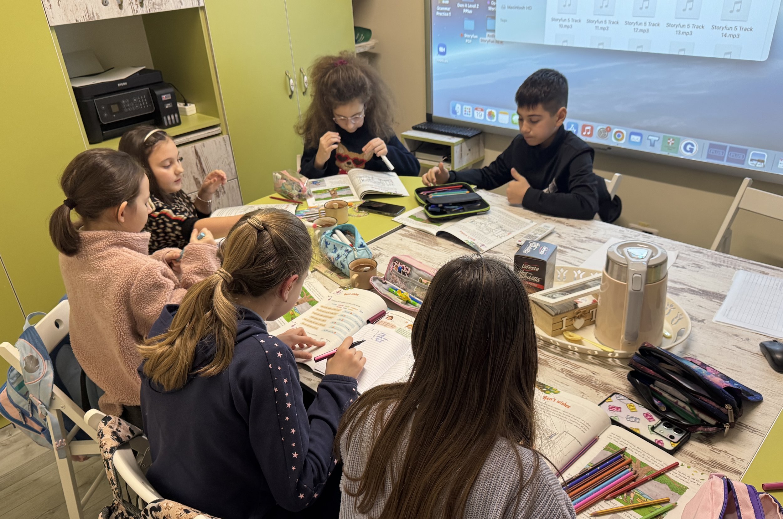 Elevi la York Rose Language School din Constanța participând la o lecție de limba engleză, lucrând pe manuale și fișe de exerciții într-un mediu educațional modern, cu tablă interactivă.