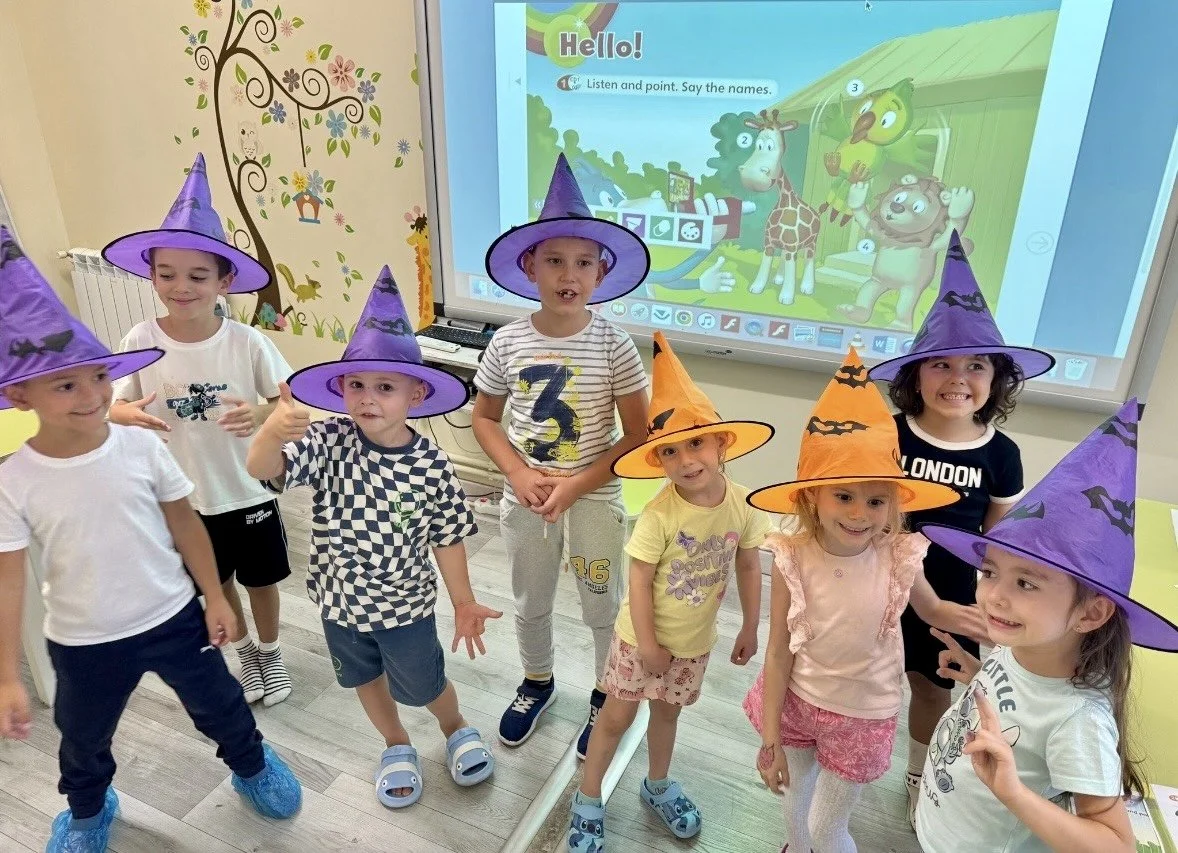 Copii la York Rose Language School din Constanța participând la o lecție tematică de limba engleză, purtând pălării de Halloween și învățând interactiv cu ajutorul tablei digitale.