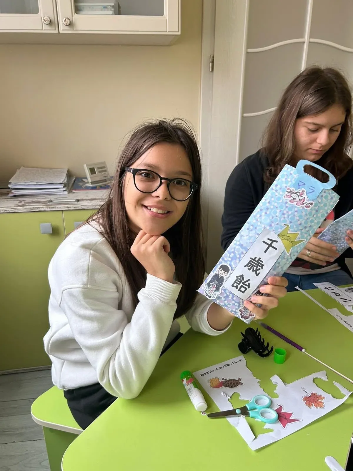 O fetiță zâmbitoare arătând o pungă tradițională pentru dulciuri Chitose Ame realizată în timpul orelor de limba japoneză la York Rose Constanta