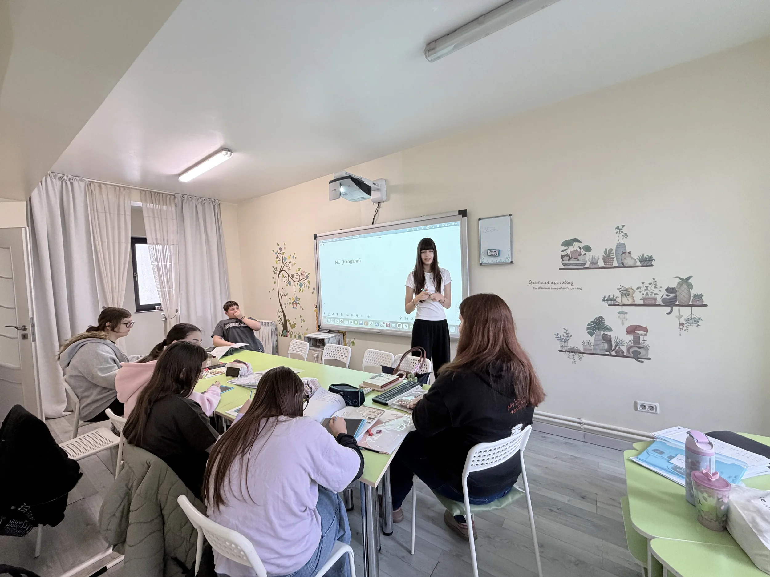 O elevă adolescentă prezentând un exercițiu la ecranul digital în fața profesoarei și a colegilor, la școala de limbi străine York Rose in Constanta