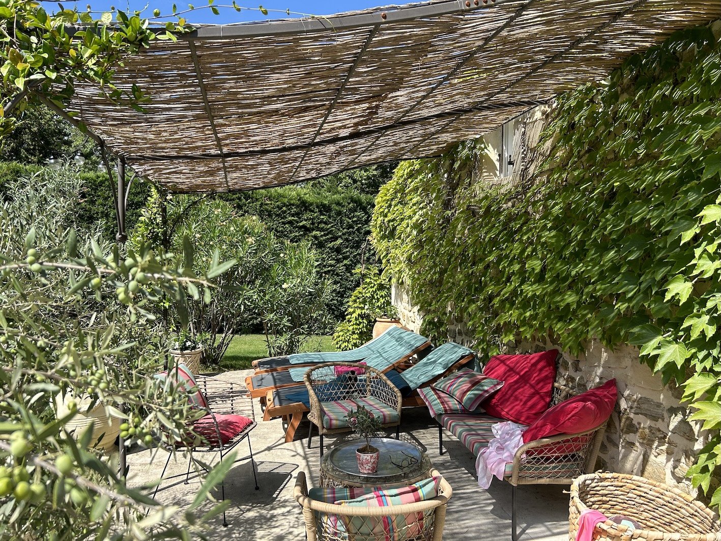 Gemütlicher Gartenbereich mit stilvollen Sitzmöbeln, Sonnenliegen, Sonnenschirm und üppigem Grün auf einer Terrasse