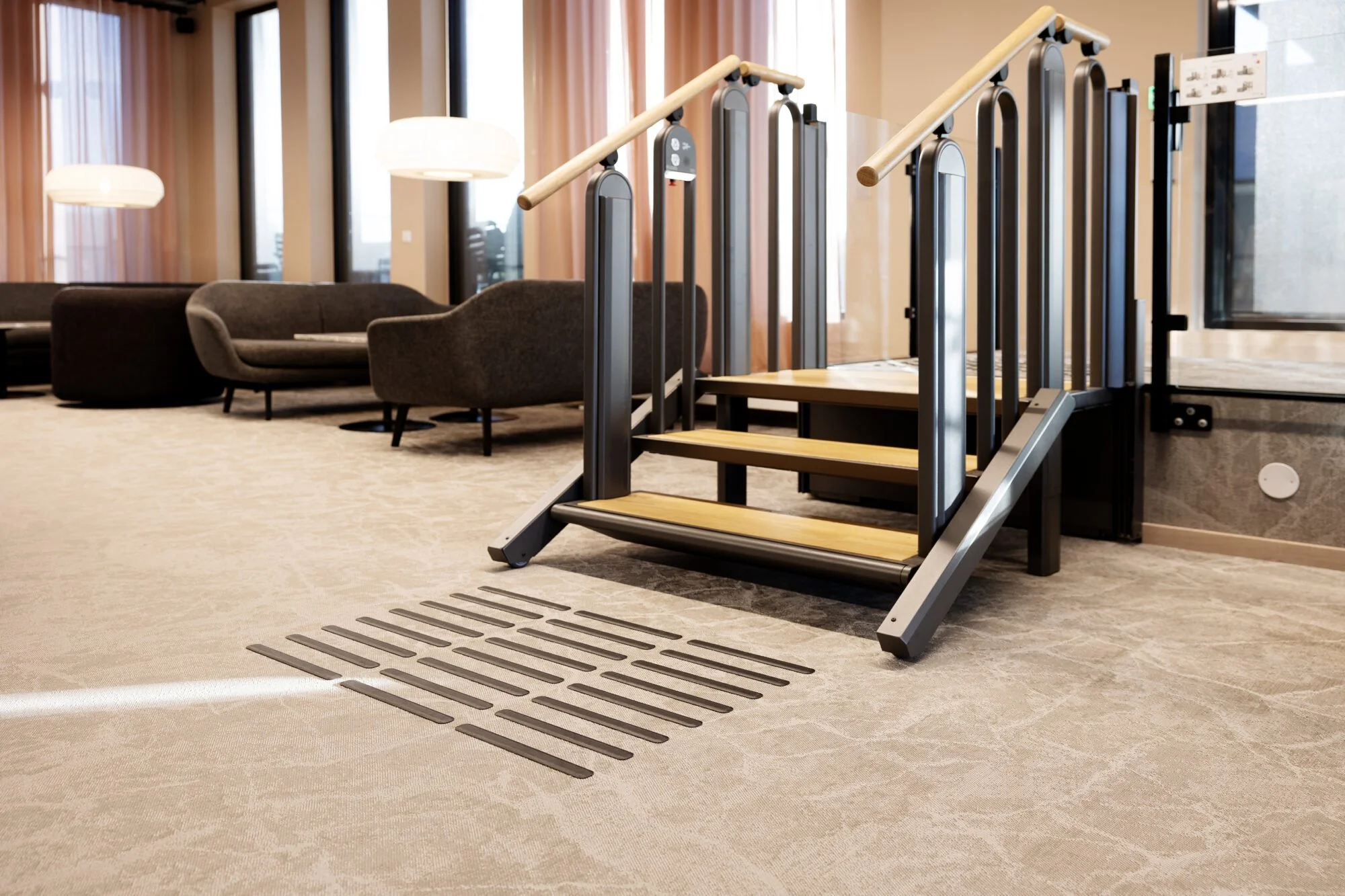 Innendørs område med rullestolrampe, samt ulike lenestoler og sofaer.