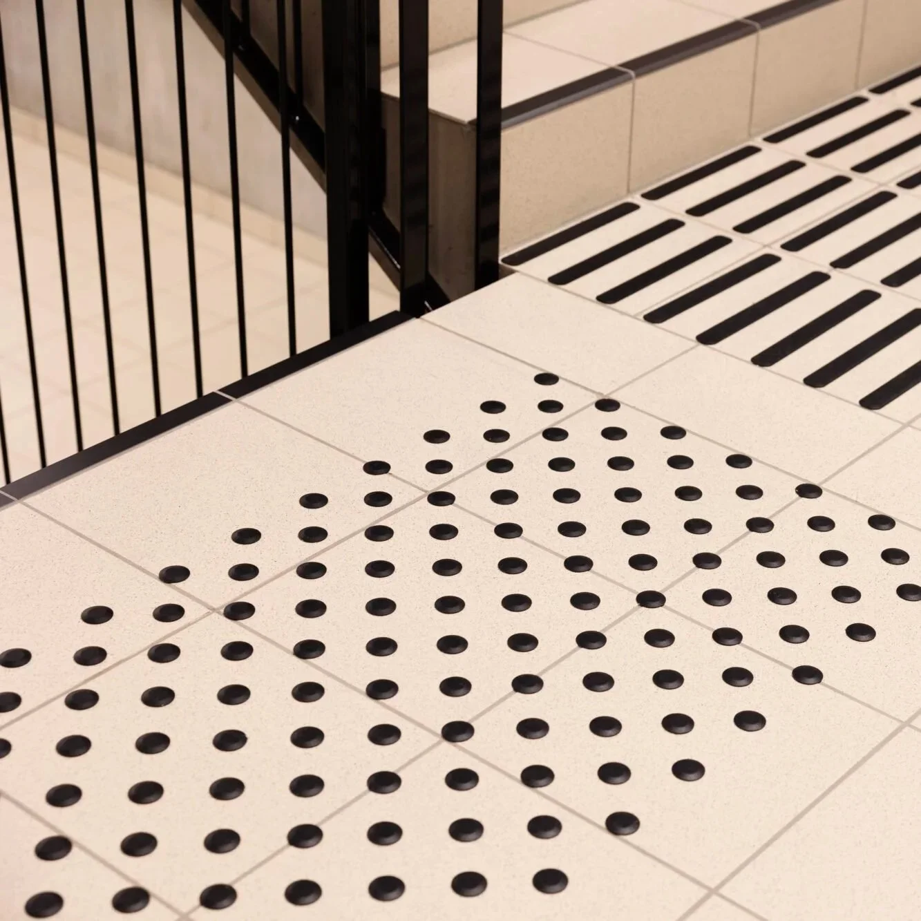 Tegnet golv med svarte runde støtter på hvit overflate, foran et svart metallgjerde.
