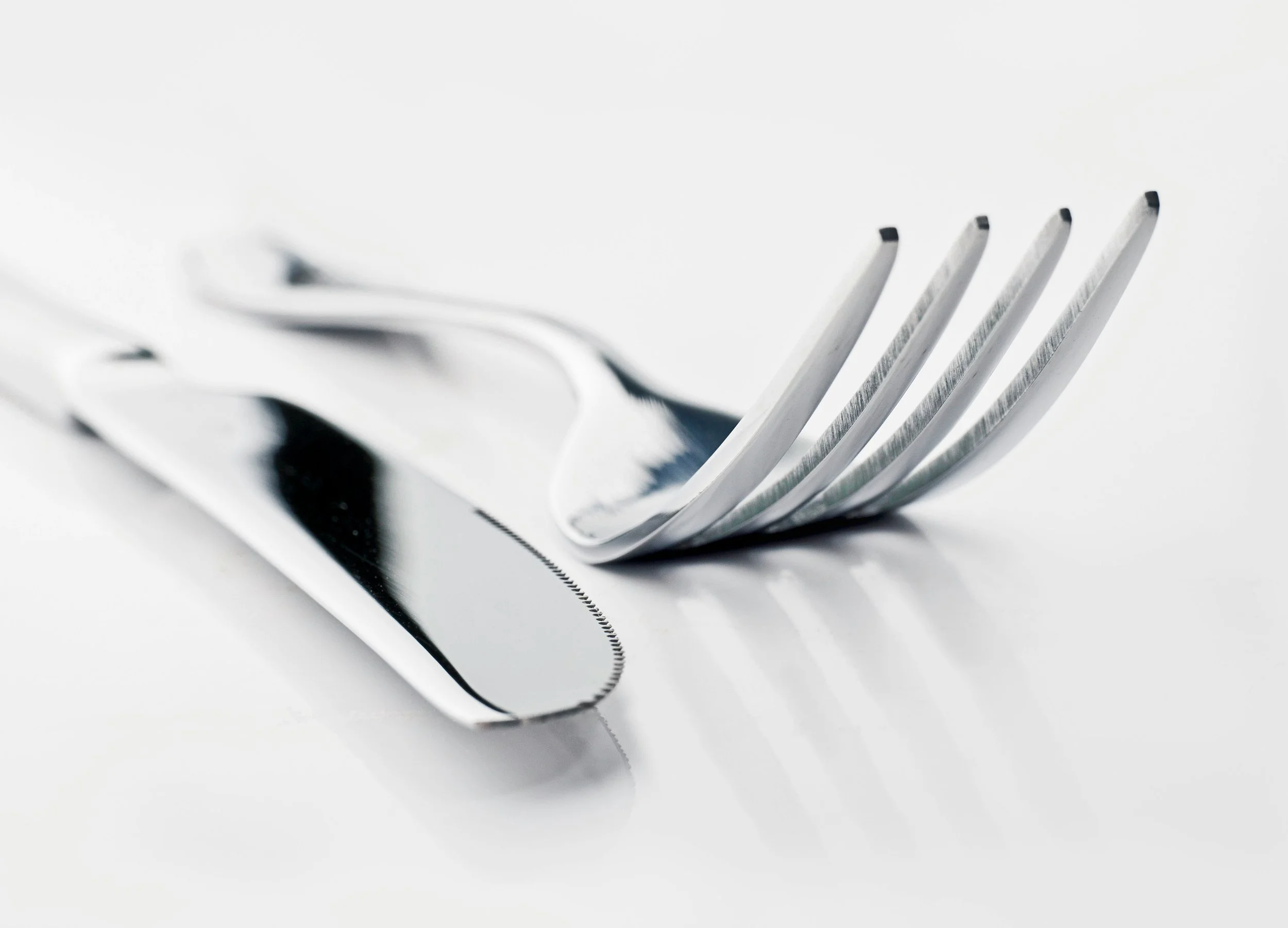 A close-up of a silver fork with the tines bent upward, resting on a reflective surface.