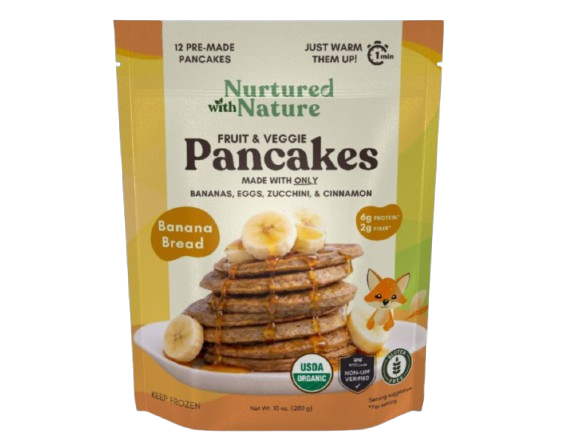 Package of nurtured with nature fruit and veggie pancakes with banana bread flavor. The package shows stacked pancakes topped with banana slices, alongside bananas and a small cartoon fox, emphasizing organic ingredients and nutritional benefits.