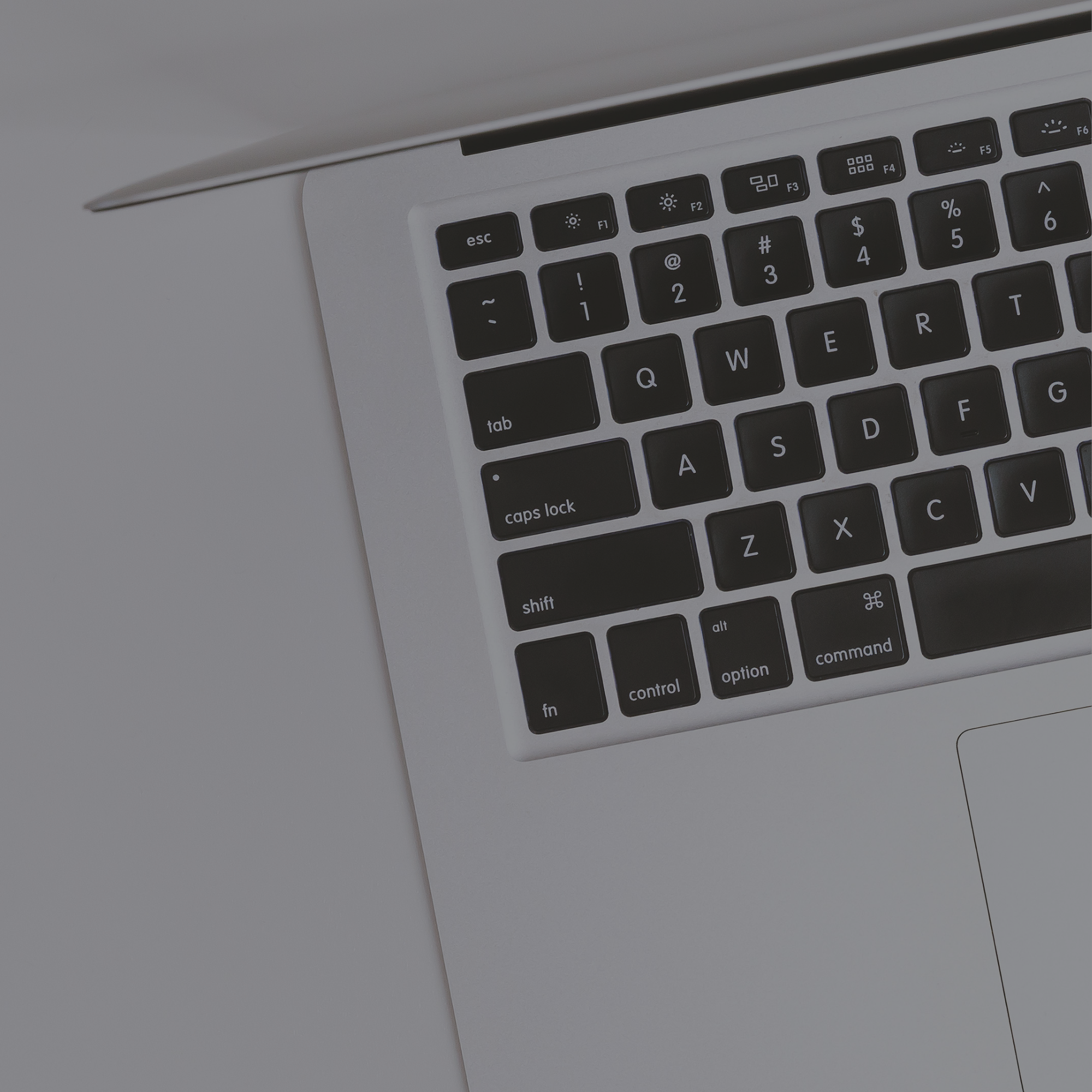Close-up of a laptop keyboard on a clean desk, representing graphic design and creative marketing services by Seven4 Marketing.