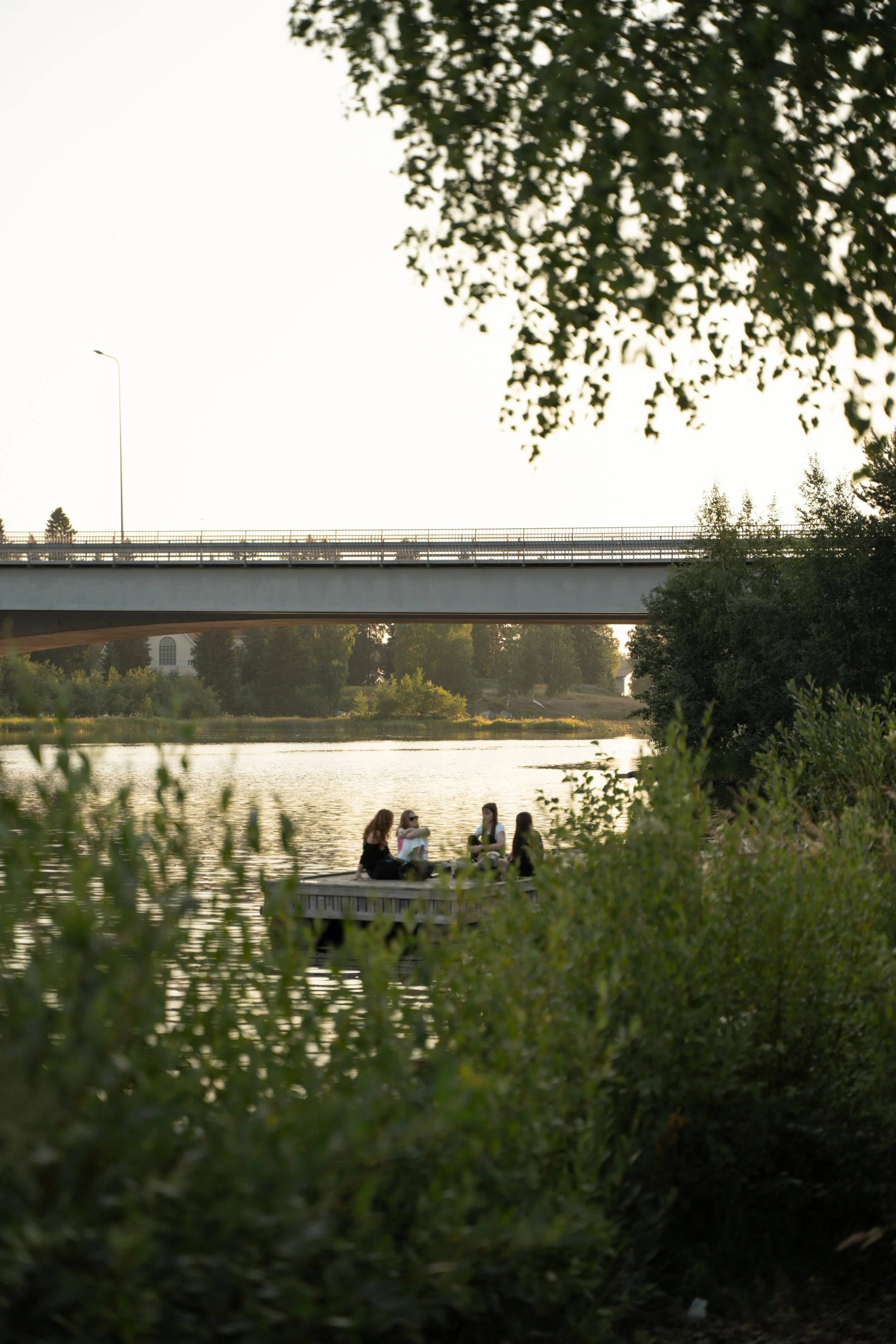 Teinit istumassa laiturilla kesäillassa Haukiputaalla
