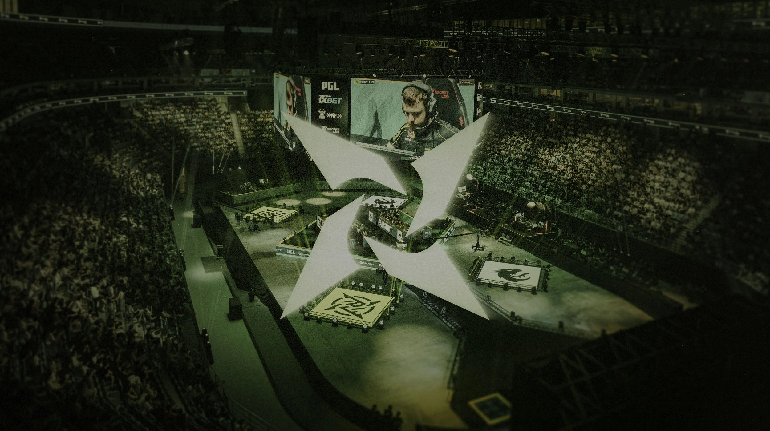 An esports event with a large crowd in a stadium, a stage with gaming screens, and a large illuminated logo at the center.