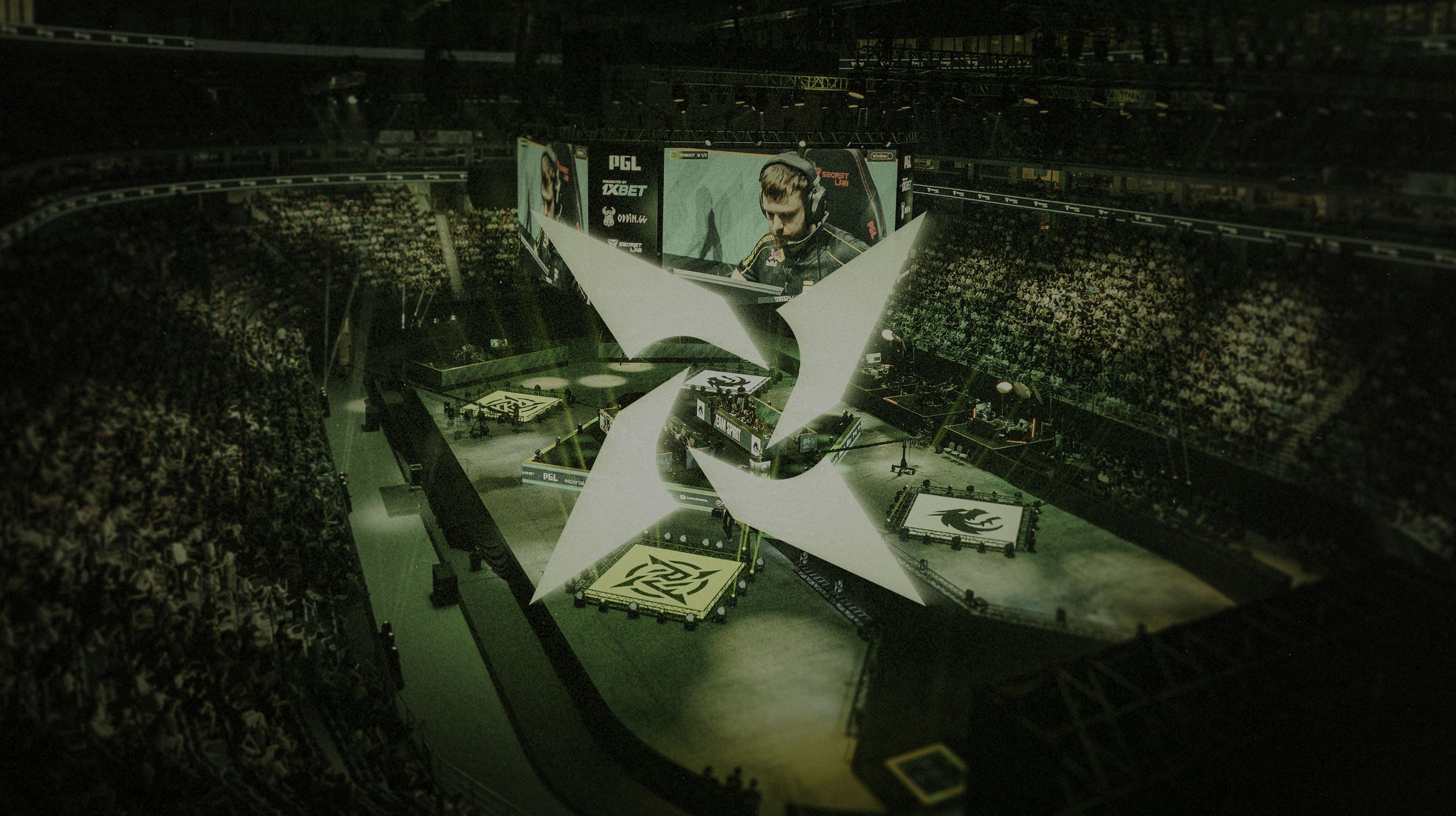 An indoor esports arena with a large stage, multiple screens, and a crowd of spectators. The stage features a prominent star-shaped structure and branding related to PGL, with a large video screen showing a focused player at a gaming tournament.