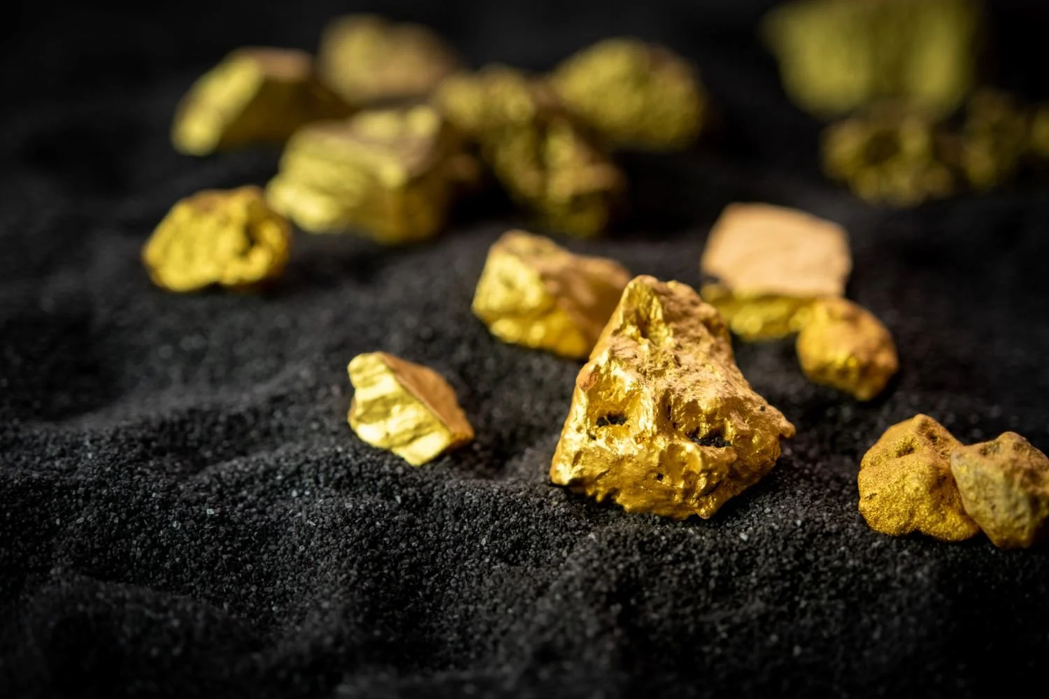 Close up of raw gold nuggets on dark sand, illustrating the Good as Gold Analytics philosophy of mining raw business data for valuable insights.