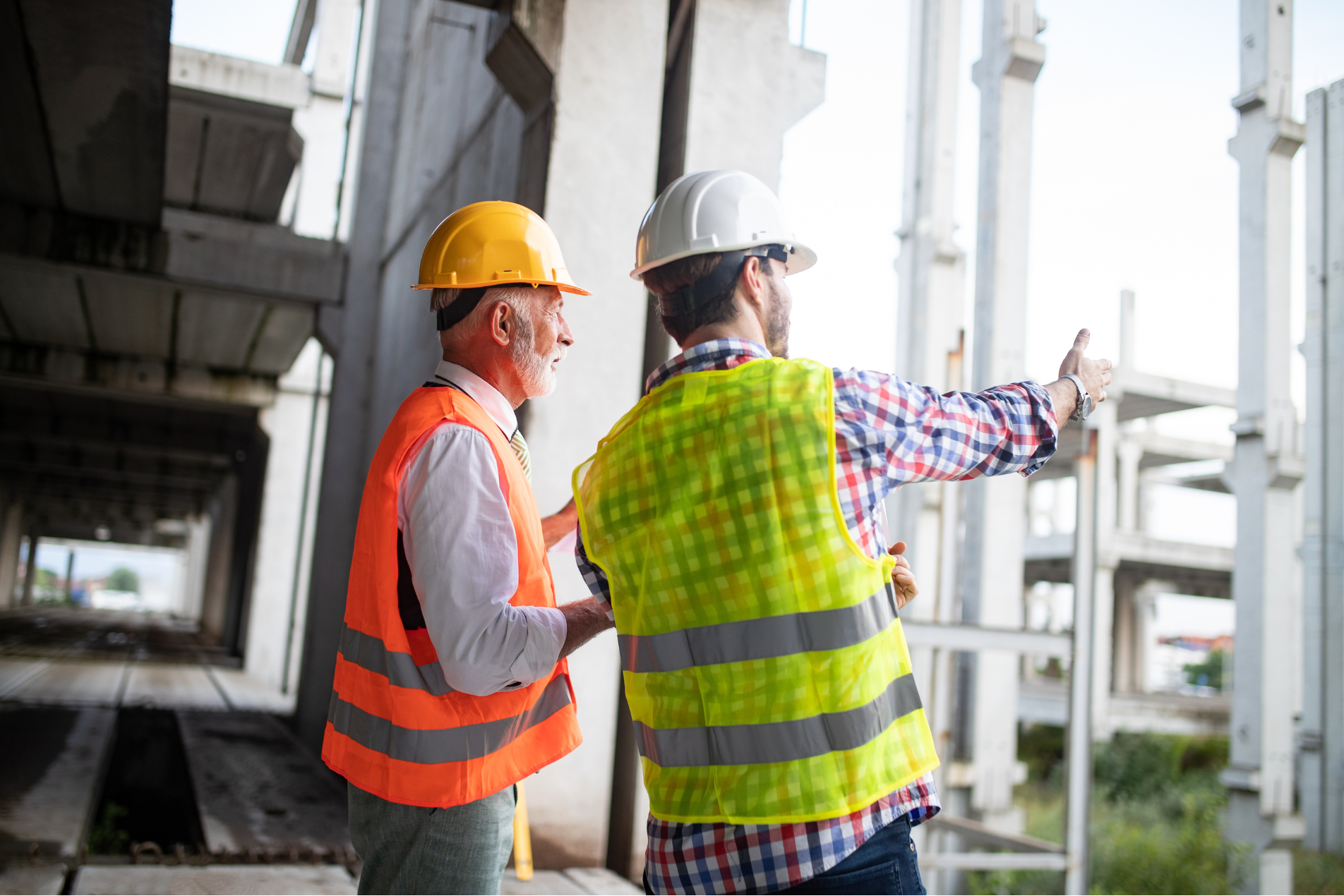 “Two site managers in PPE talking on a construction site.