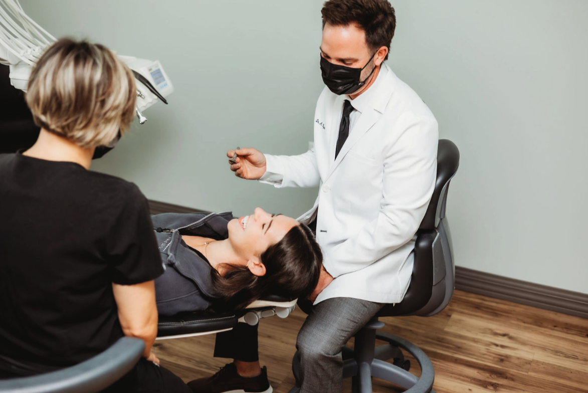 Doctor and nurse examining a smiling woman lying on a medical chair in a clinic room.