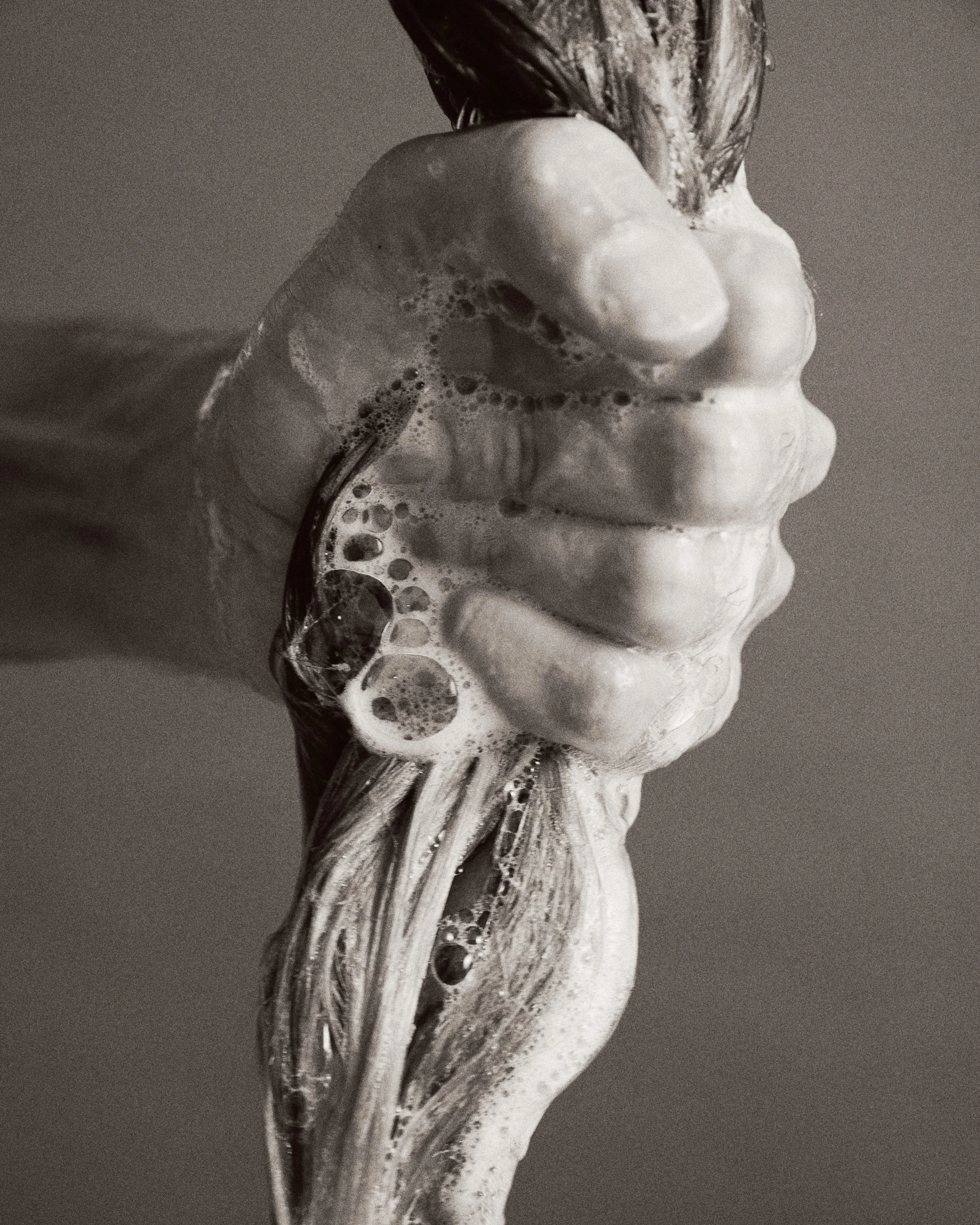 Mão ensaboada com espuma de sabonete fubando-se na pele